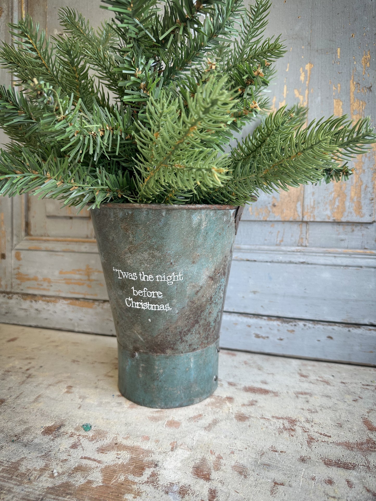 A Recycled Metal Mini Christmas Tree Bucket With A Hand Painted Quote