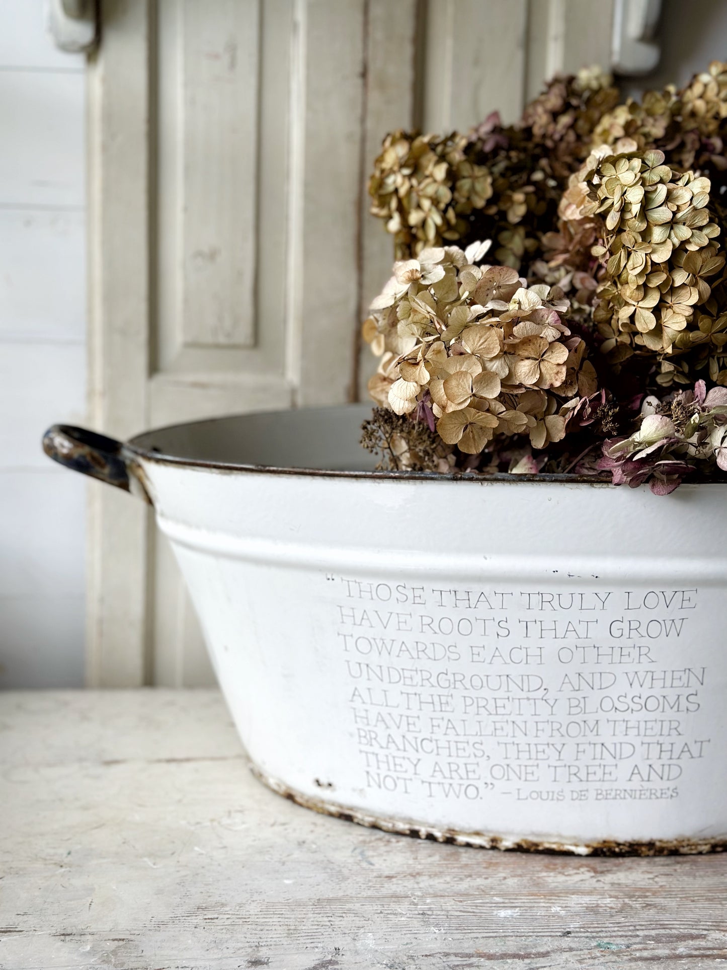 A rustic time worn white enamel oval bath hand painted with a quote.