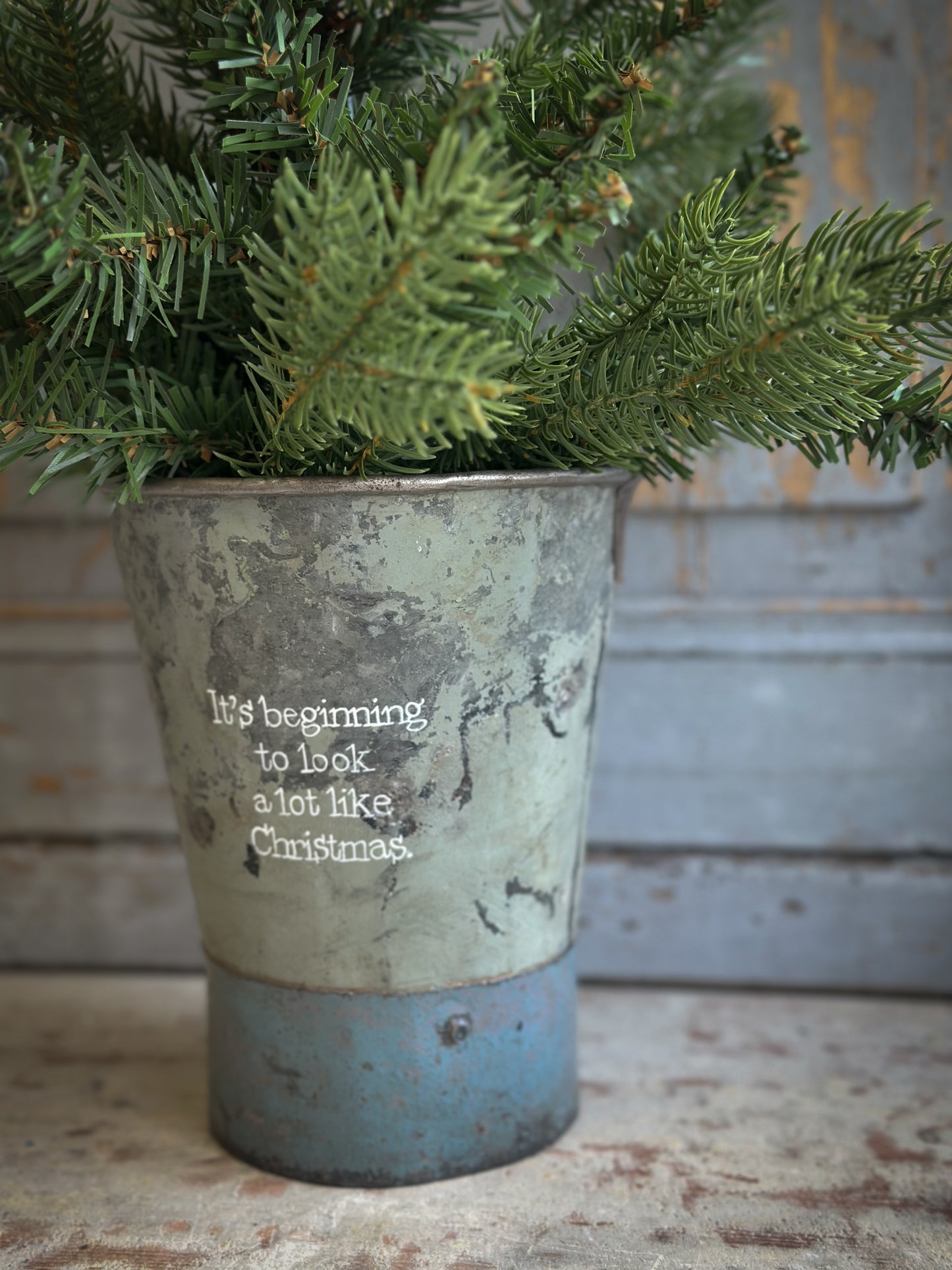 A Recycled Metal Mini Christmas Tree Bucket With A Hand Painted Quote