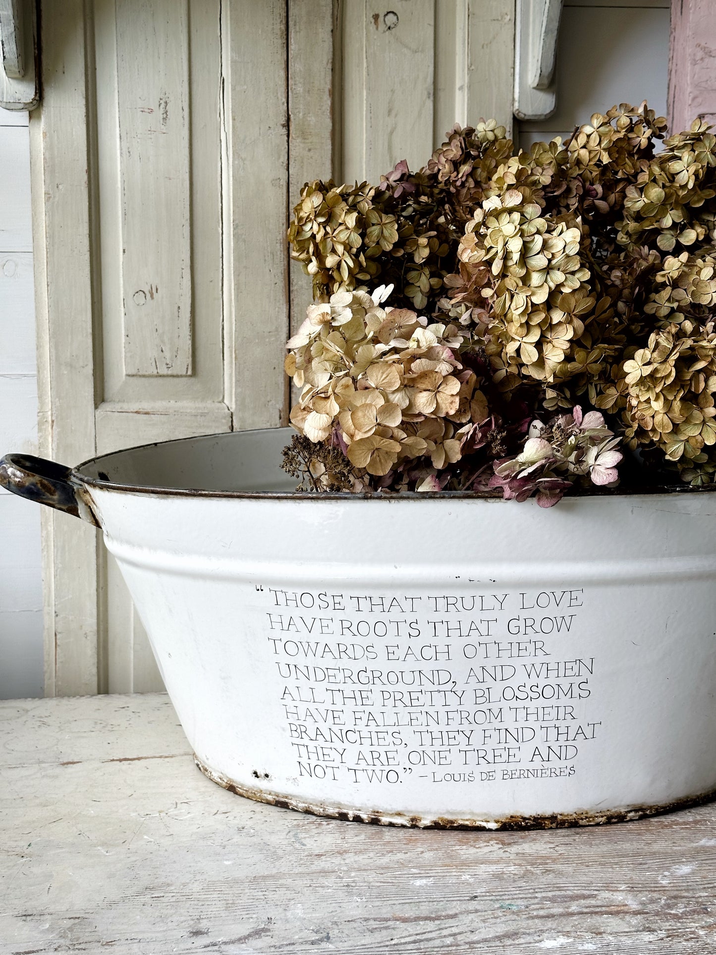 A rustic time worn white enamel oval bath hand painted with a quote.