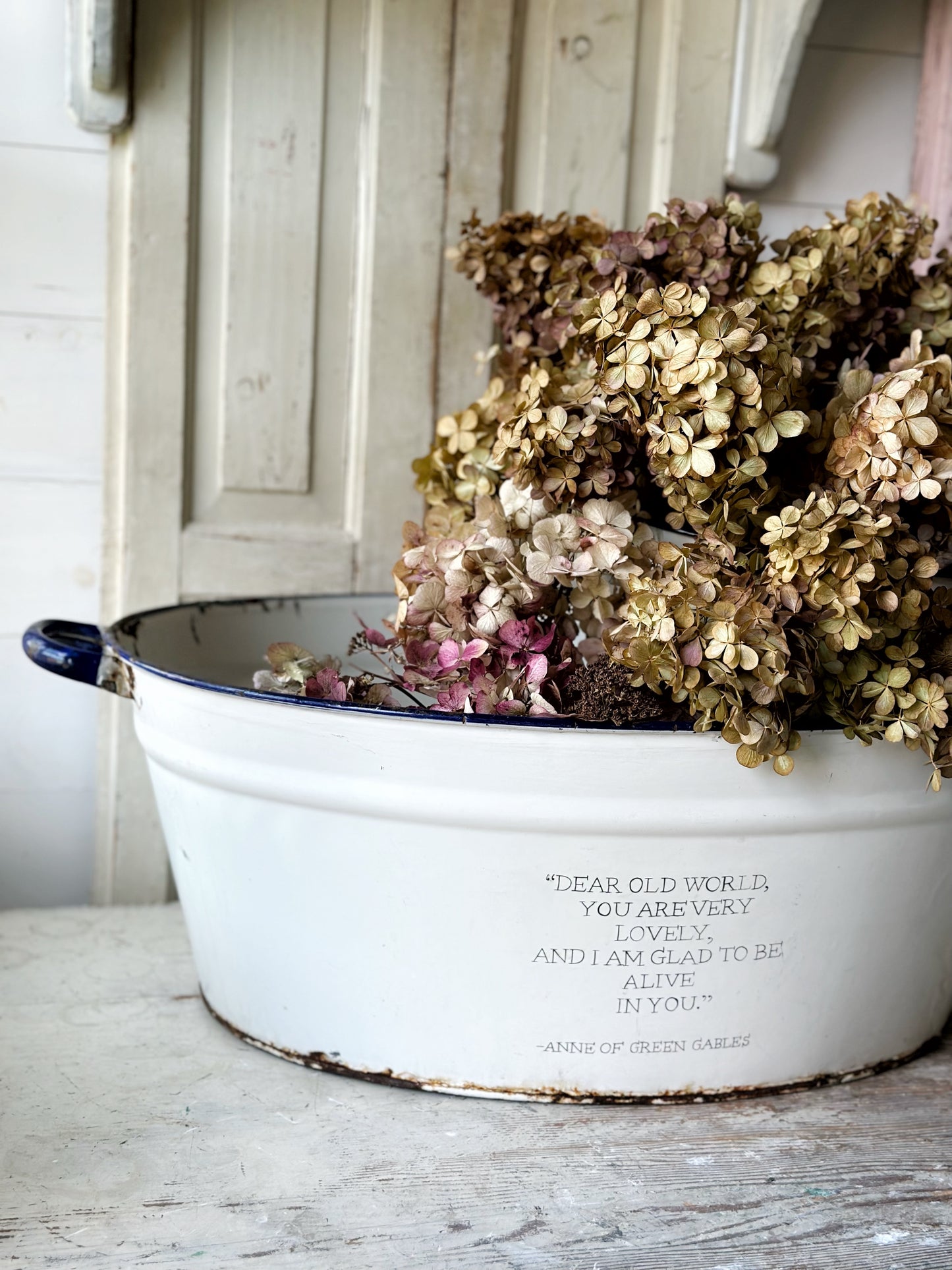 A rustic time worn white enamel oval bath hand painted with a quote.