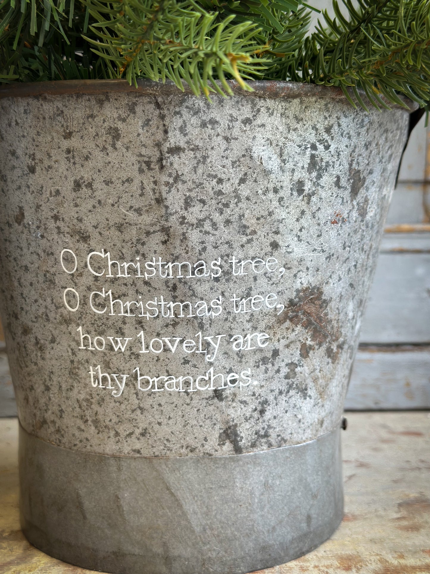 A Recycled Metal Small Christmas Tree Bucket With A Hand Painted Quote