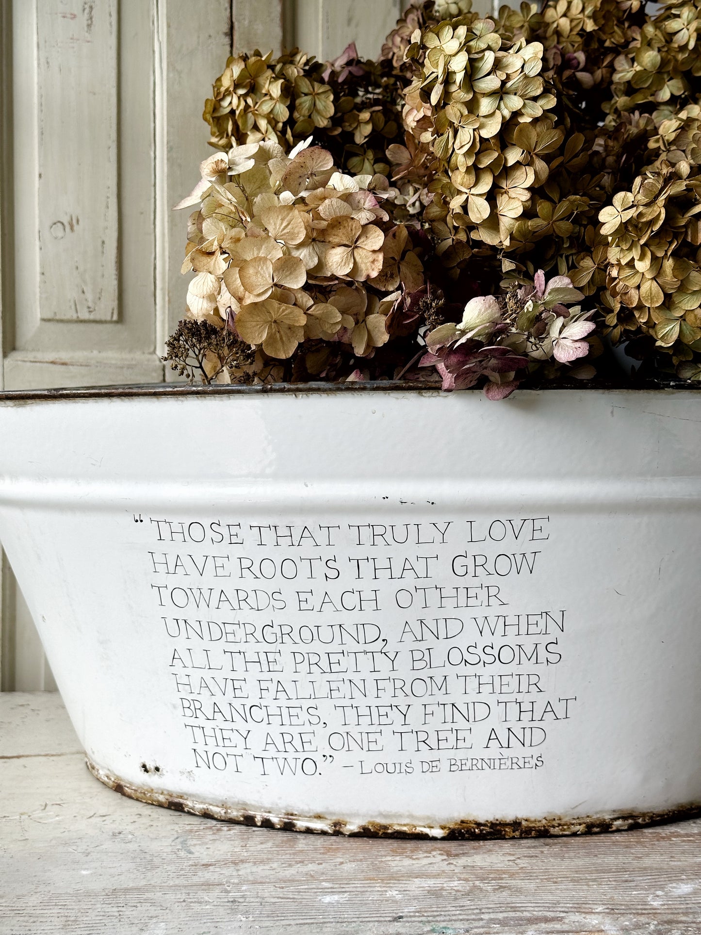 A rustic time worn white enamel oval bath hand painted with a quote.