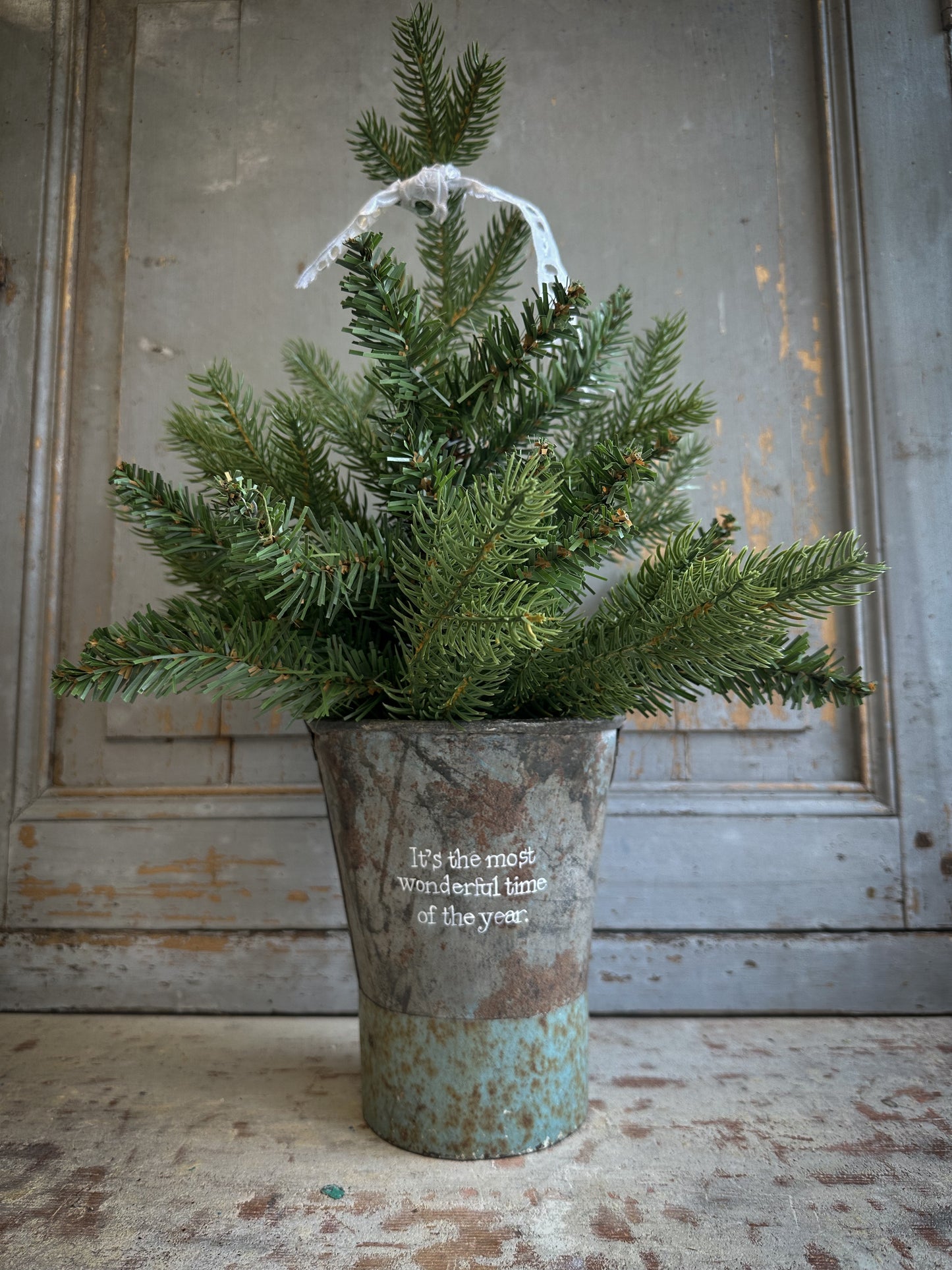 A Recycled Metal Mini Christmas Tree Bucket With A Hand Painted Quote
