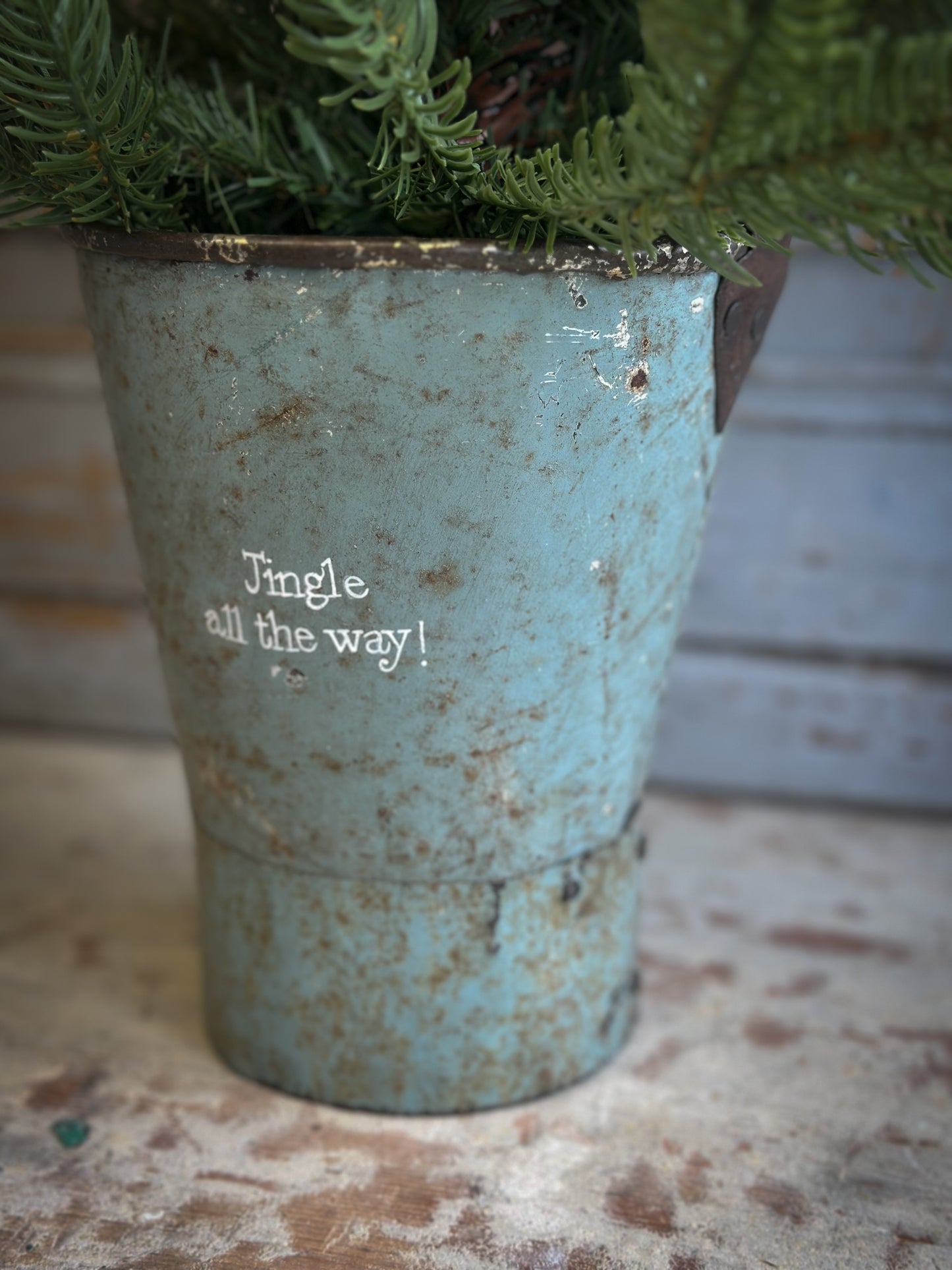 A Recycled Metal Mini Christmas Tree Bucket With A Hand Painted Quote