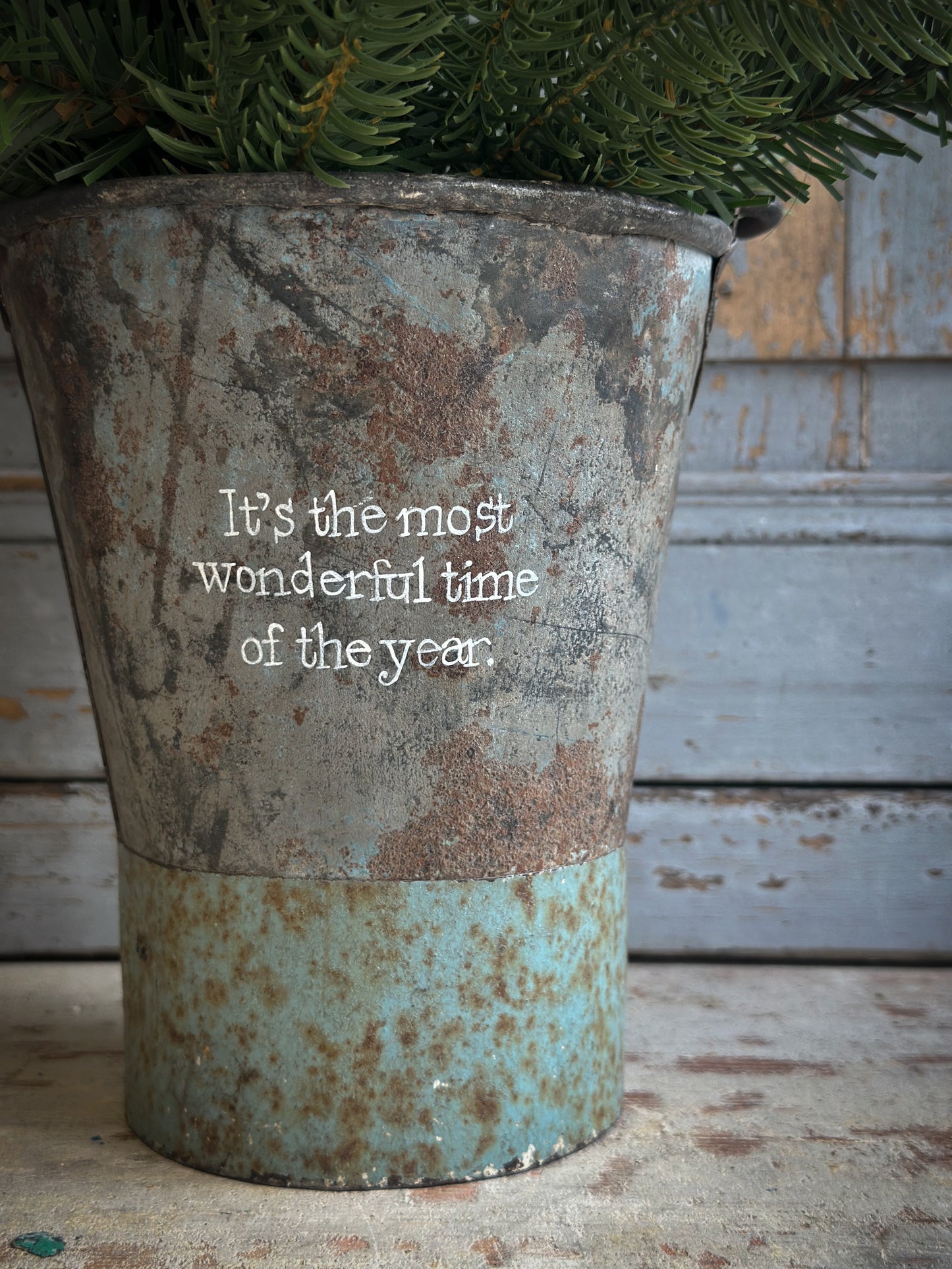 A Recycled Metal Mini Christmas Tree Bucket With A Hand Painted Quote