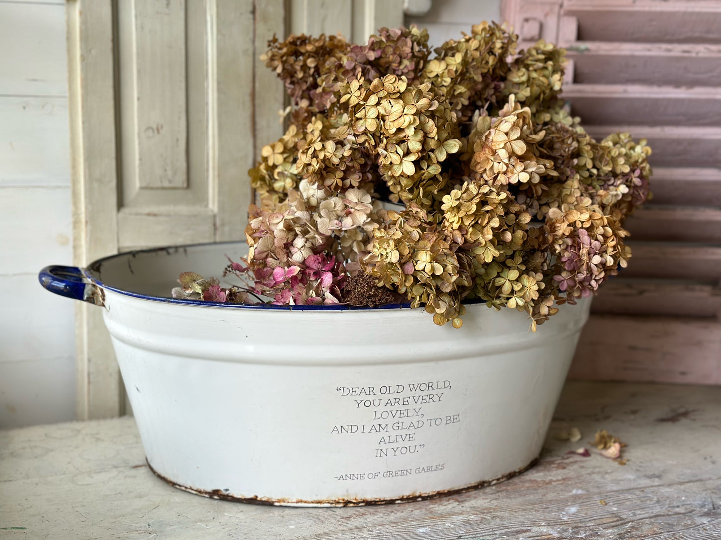 A rustic time worn white enamel oval bath hand painted with a quote.
