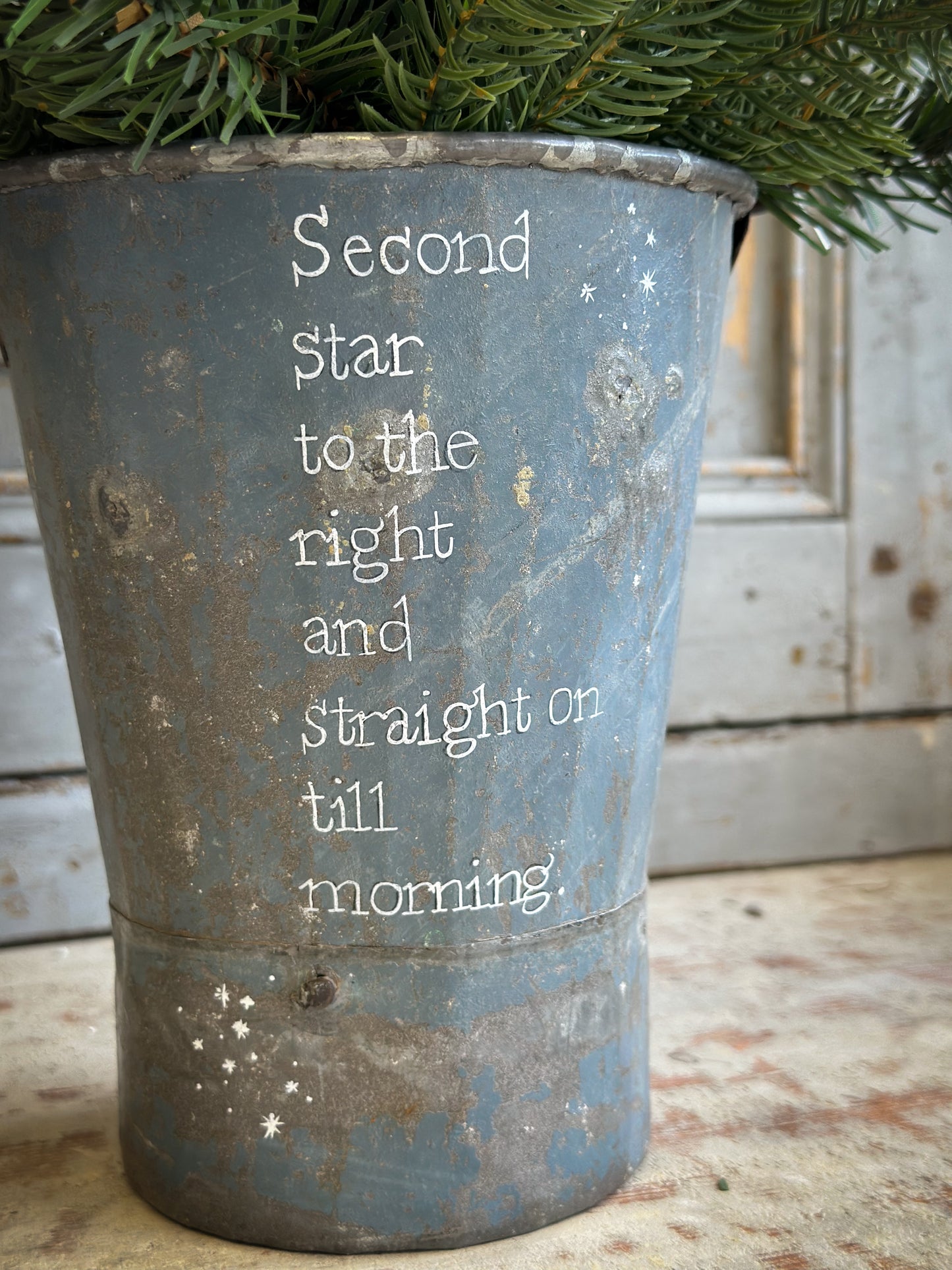 A Recycled Metal Mini Christmas Tree Bucket With A Hand Painted Quote