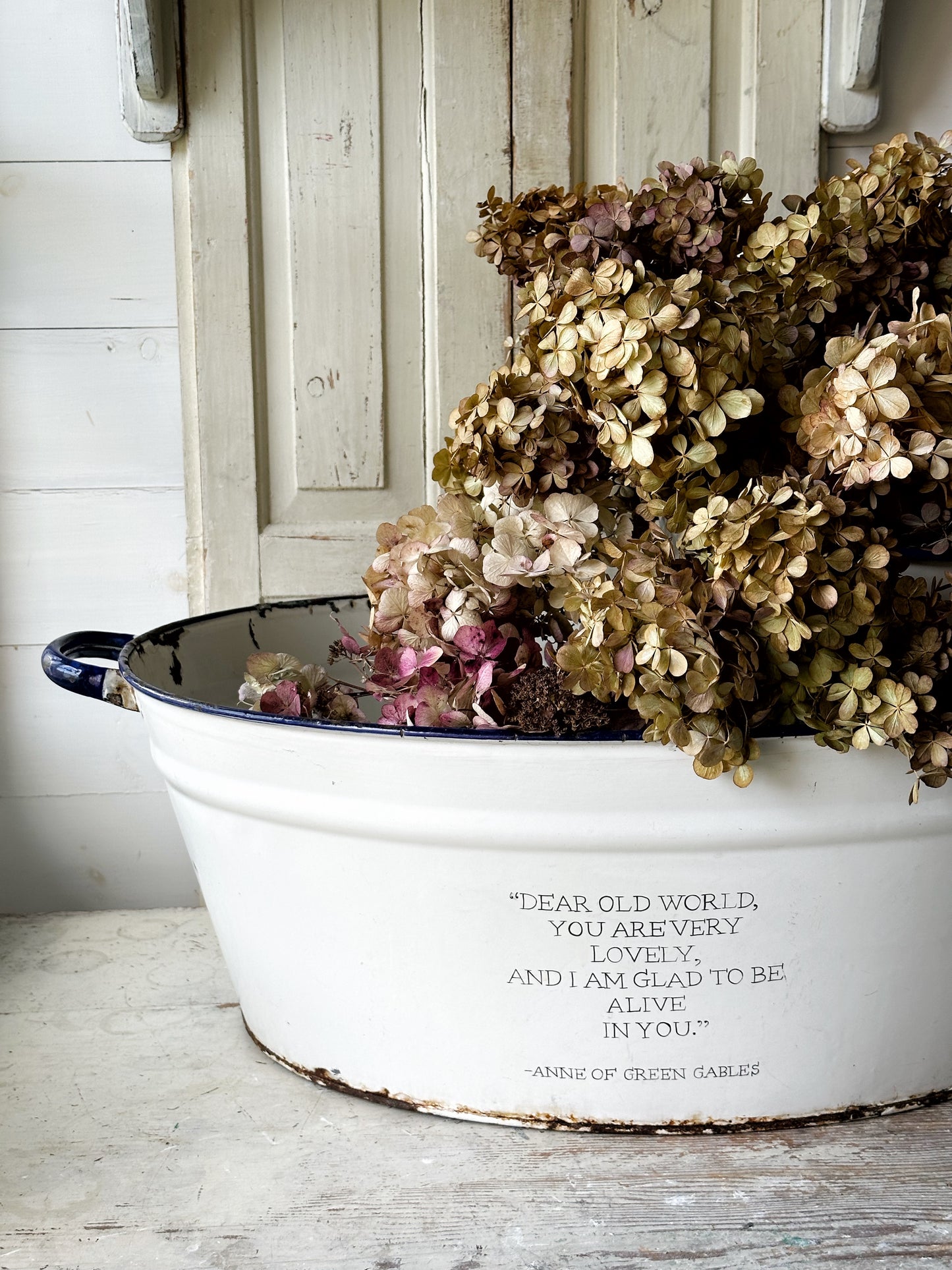A rustic time worn white enamel oval bath hand painted with a quote.