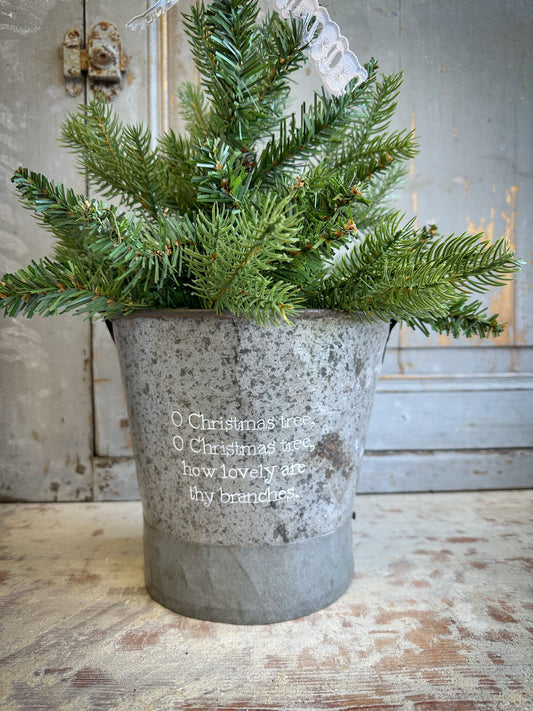 A Recycled Metal Small Christmas Tree Bucket With A Hand Painted Quote