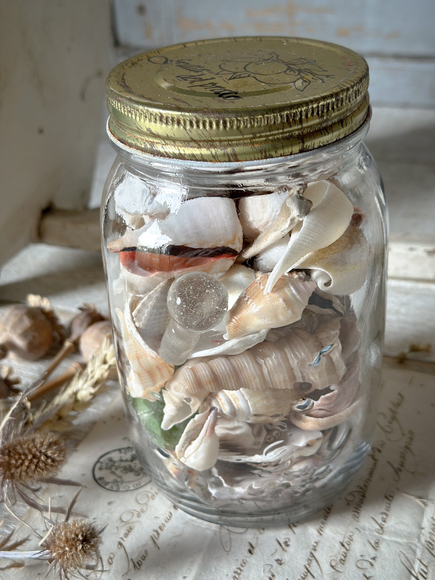 A vintage preserve bottle full of seashells