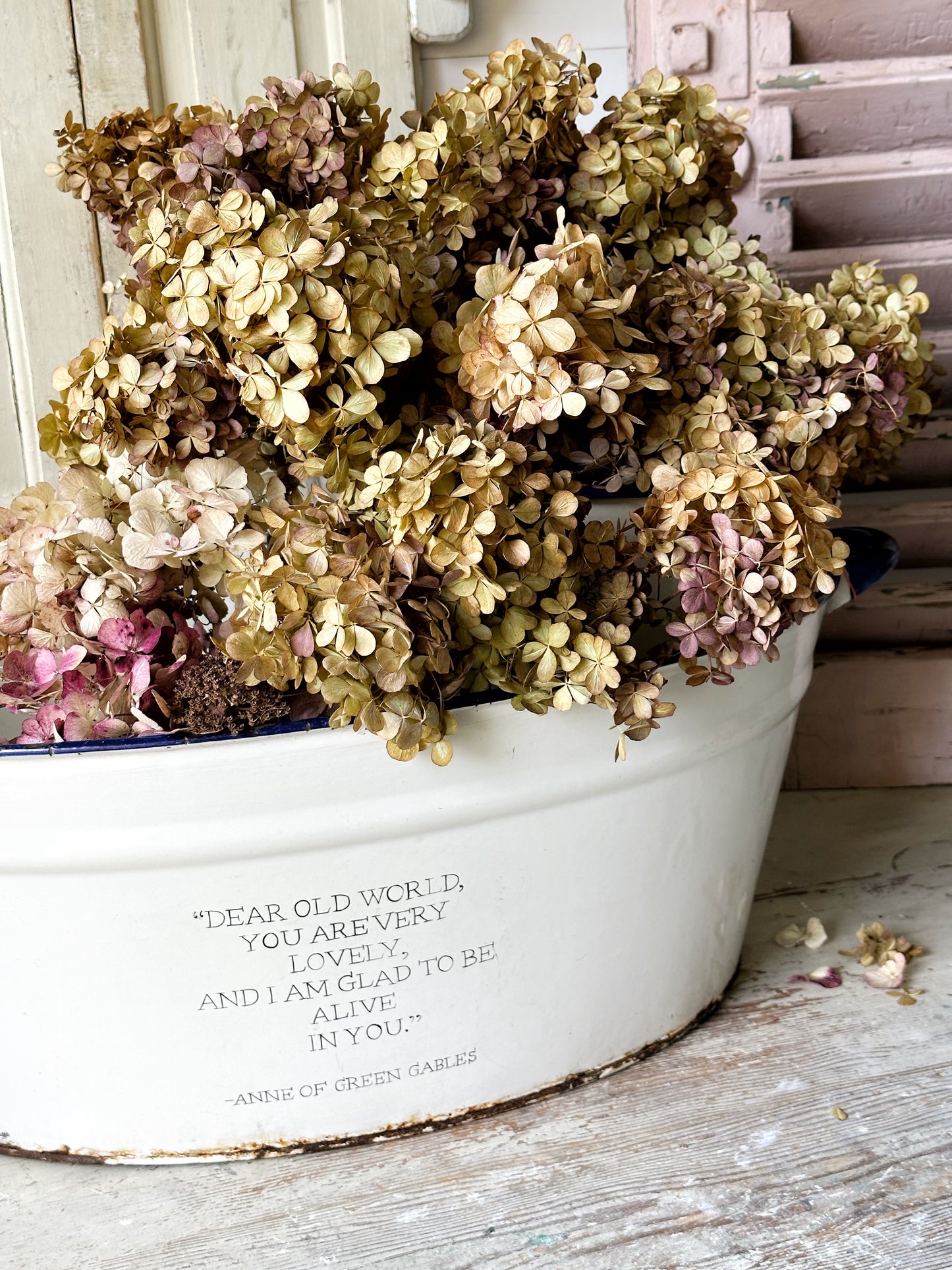 A rustic time worn white enamel oval bath hand painted with a quote.