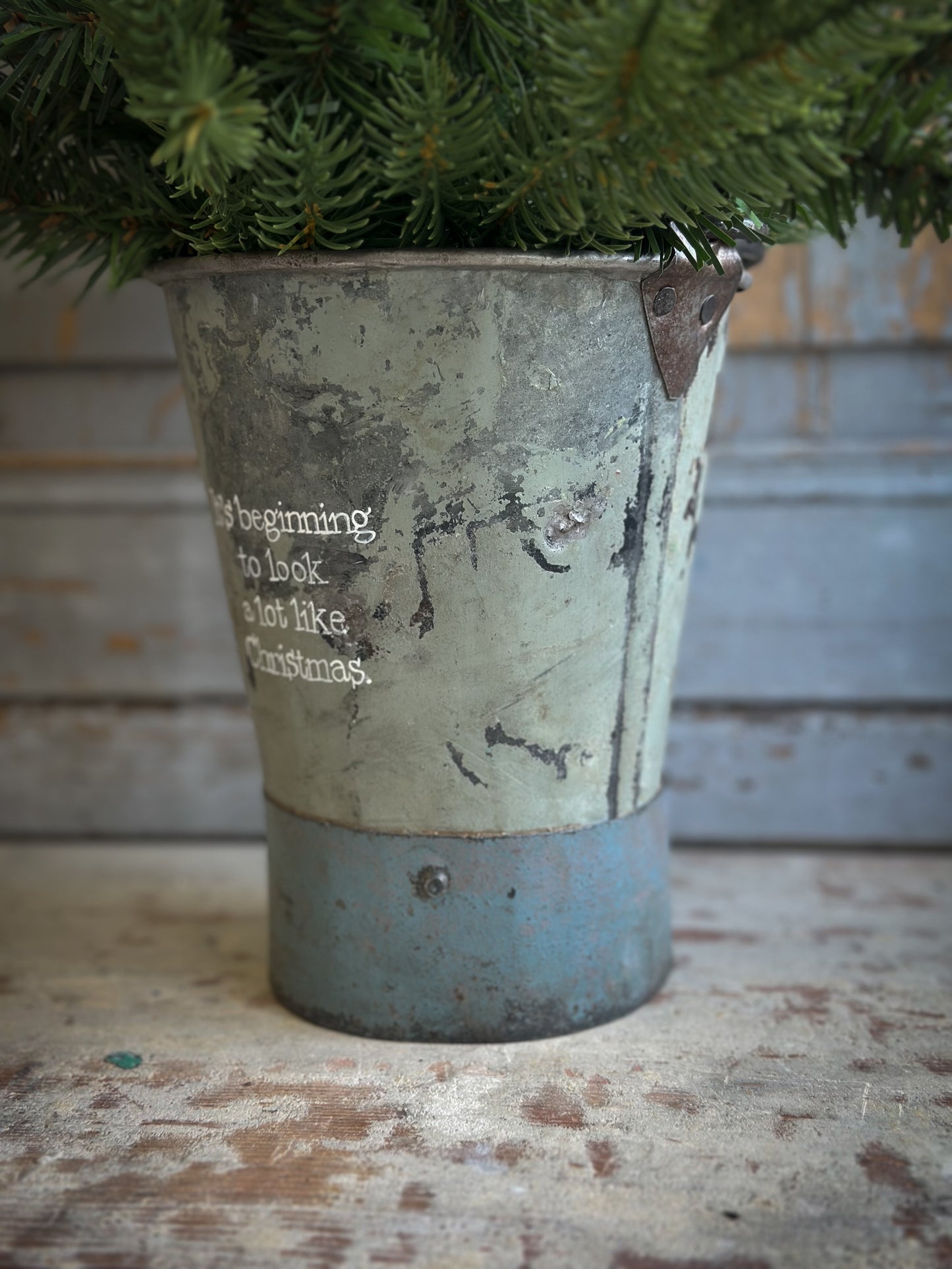 A Recycled Metal Mini Christmas Tree Bucket With A Hand Painted Quote