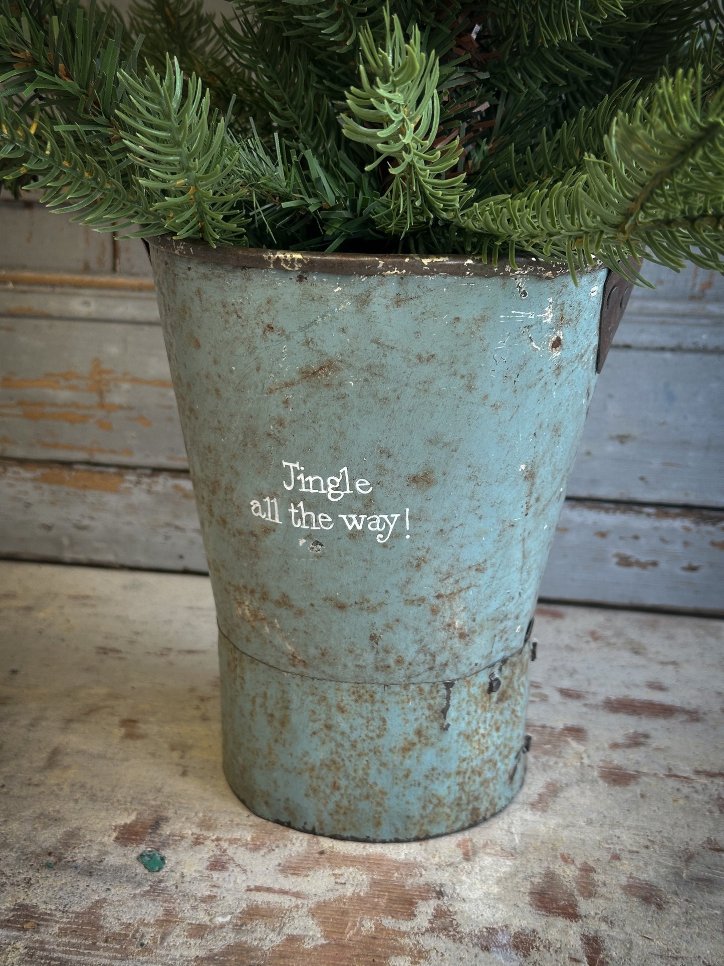 A Recycled Metal Mini Christmas Tree Bucket With A Hand Painted Quote