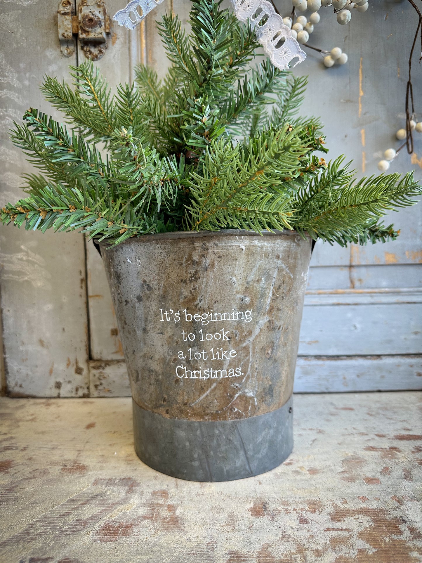 A Recycled Metal Small Christmas Tree Bucket With A Hand Painted Quote