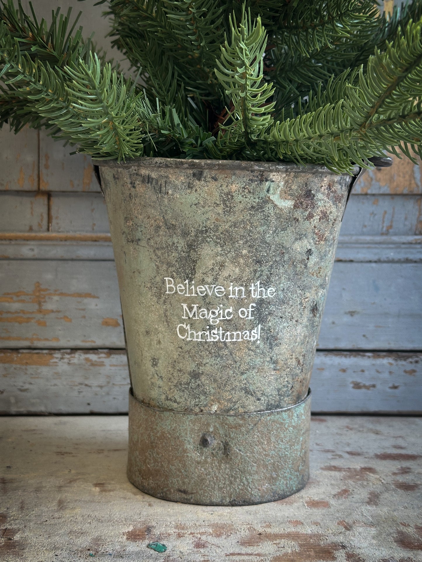 A Recycled Metal Mini Christmas Tree Bucket With A Hand Painted Quote