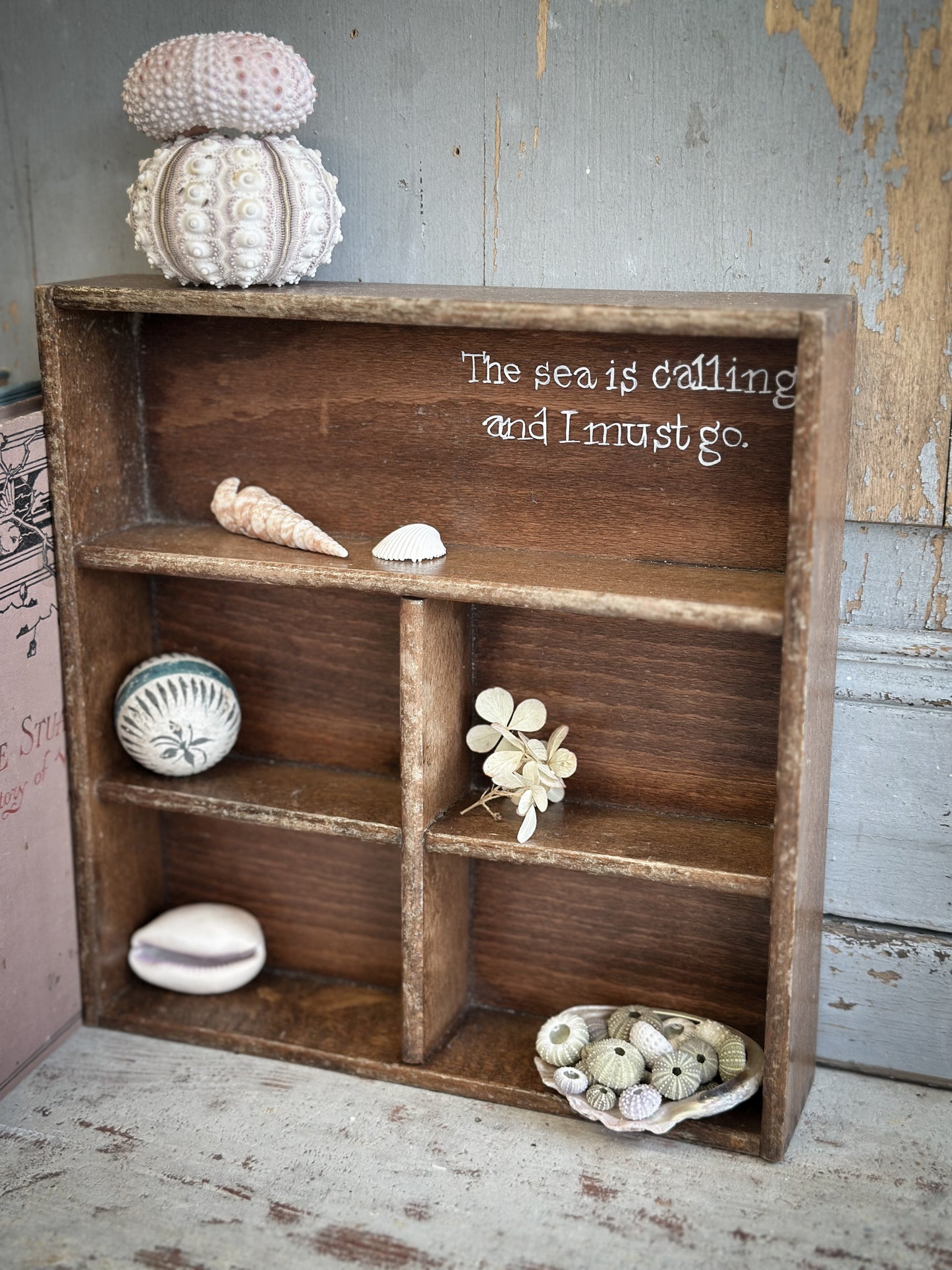 A Vintage Wooden Display Shelf With Hand Painted Quote