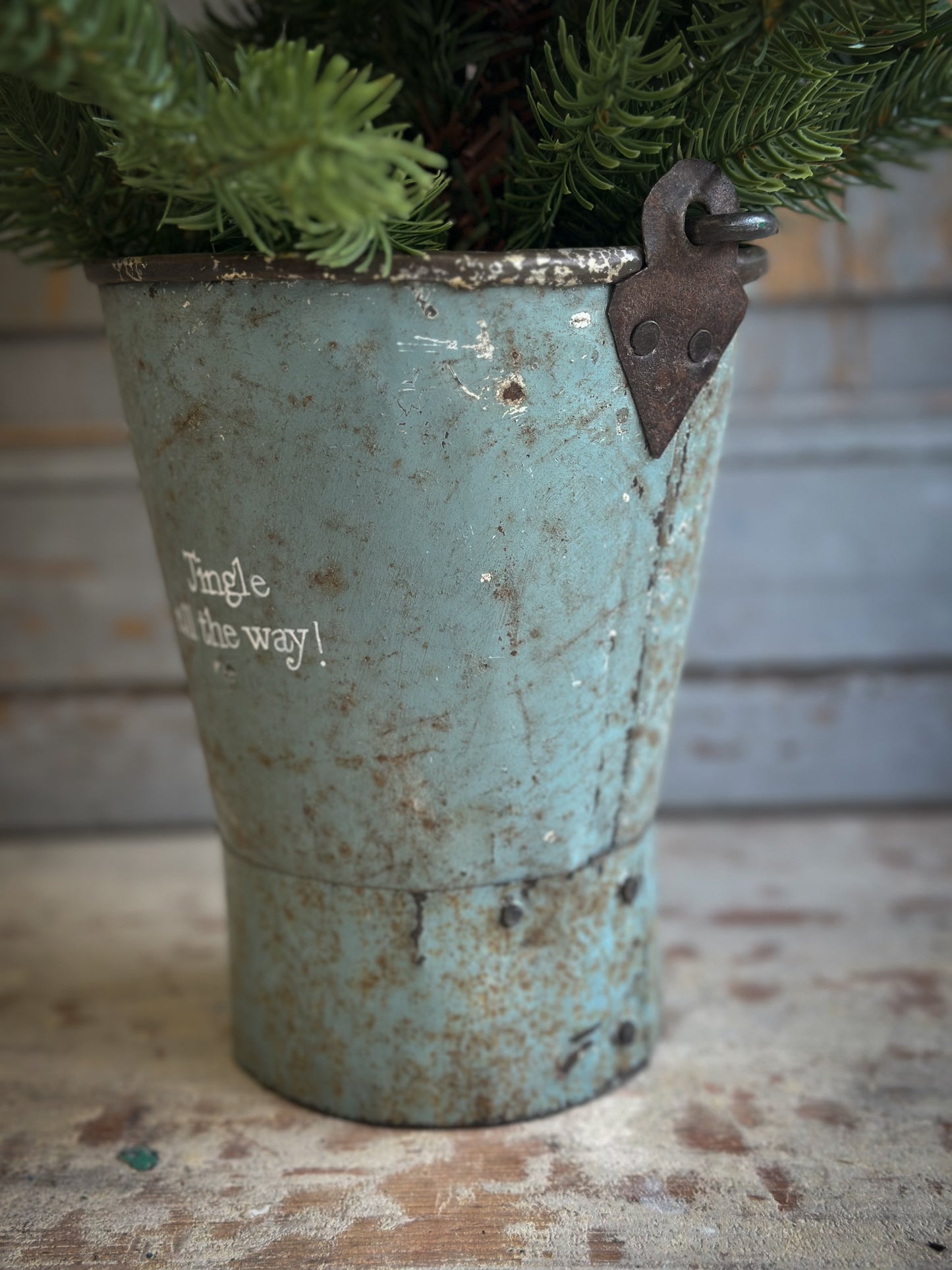 A Recycled Metal Mini Christmas Tree Bucket With A Hand Painted Quote