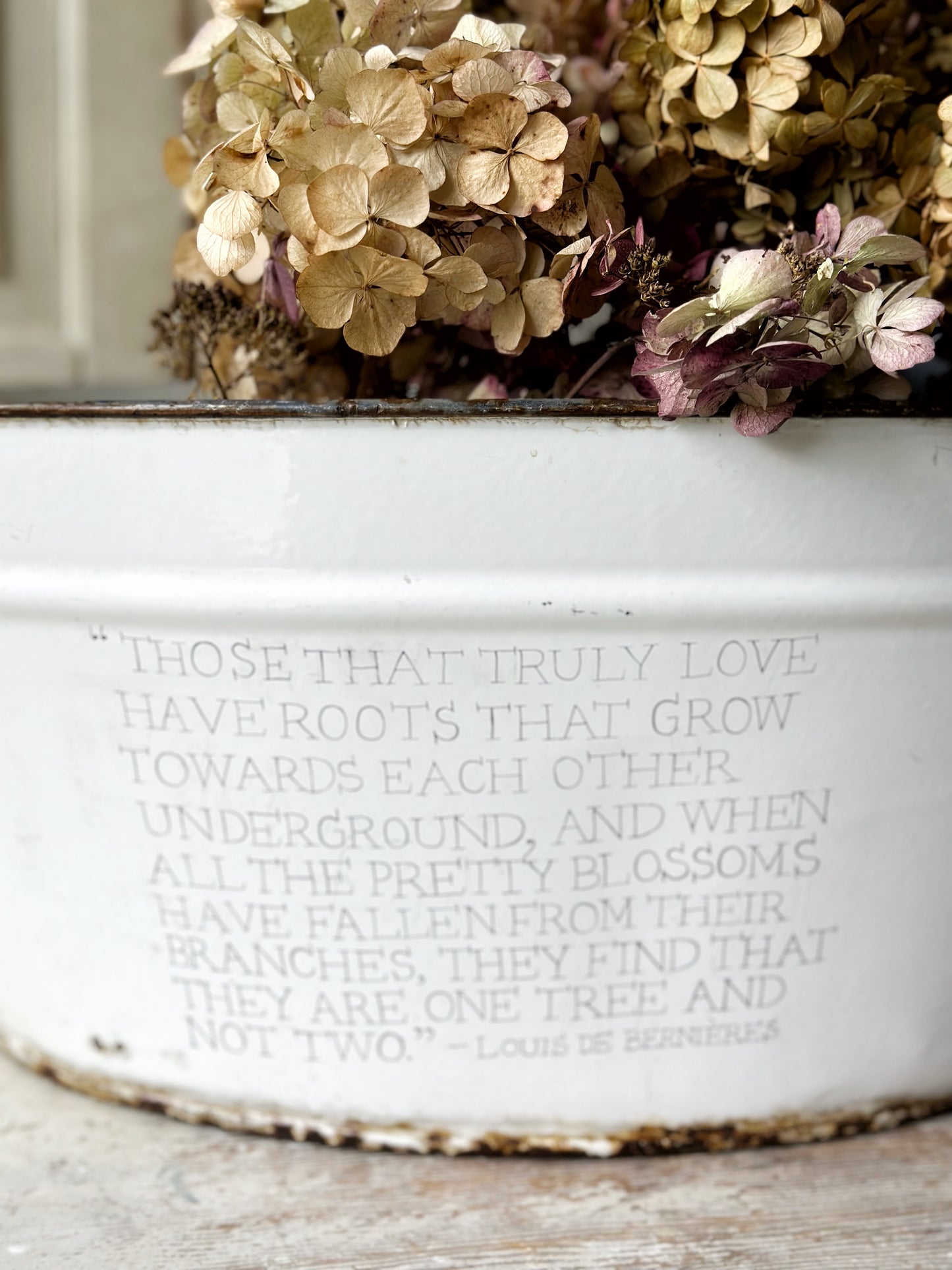 A rustic time worn white enamel oval bath hand painted with a quote.