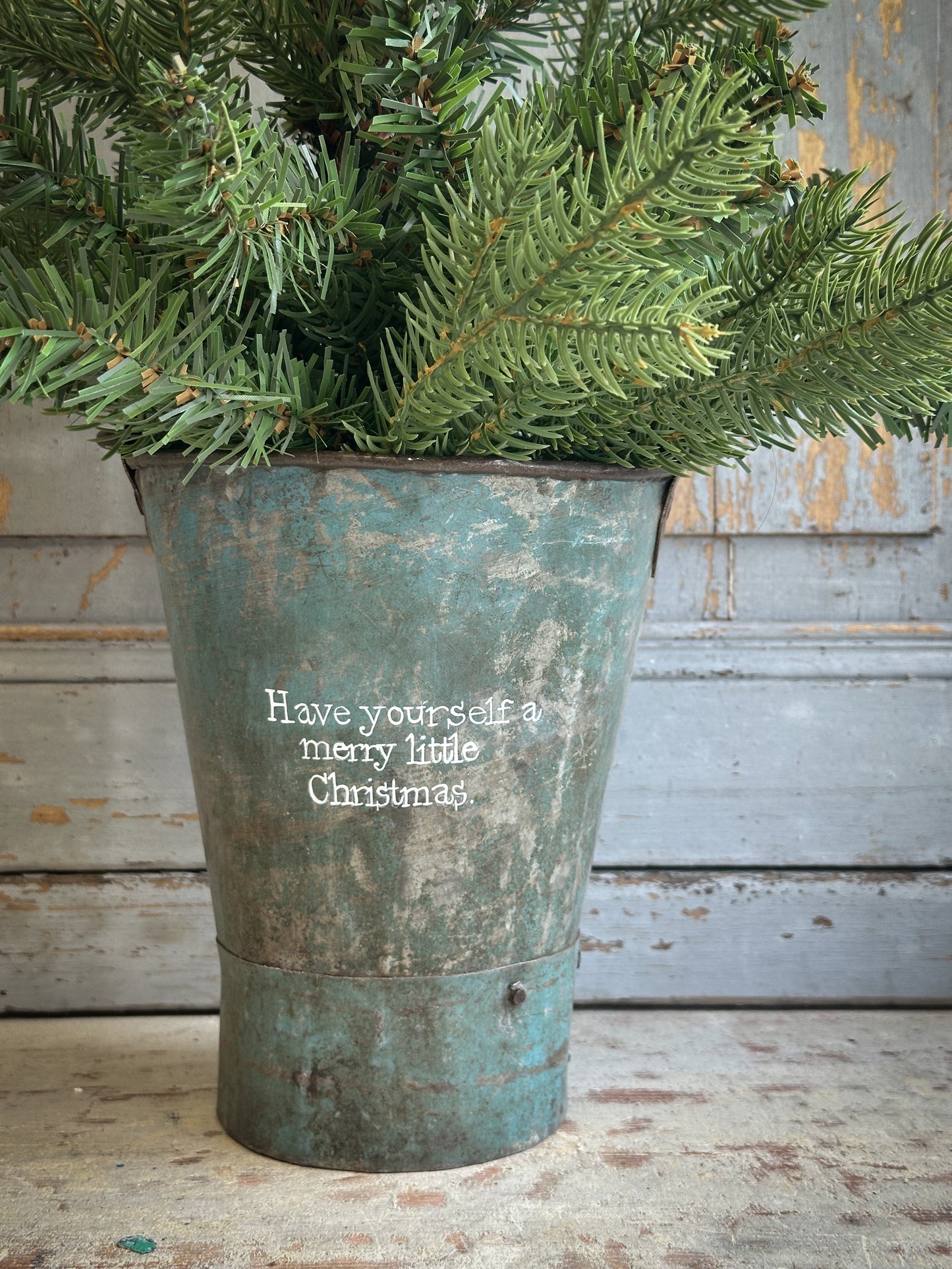 A Recycled Metal Mini Christmas Tree Bucket With A Hand Painted Quote