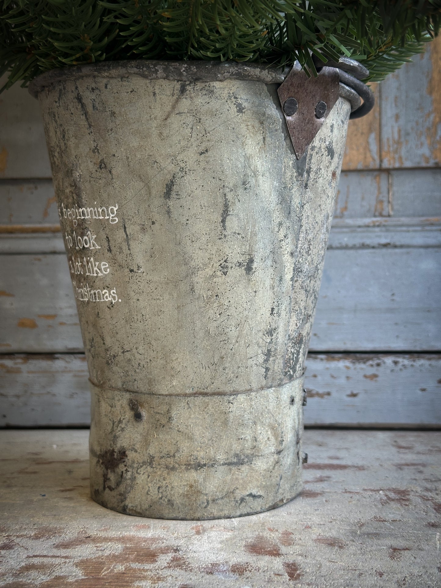 A Recycled Metal Mini Christmas Tree Bucket With A Hand Painted Quote
