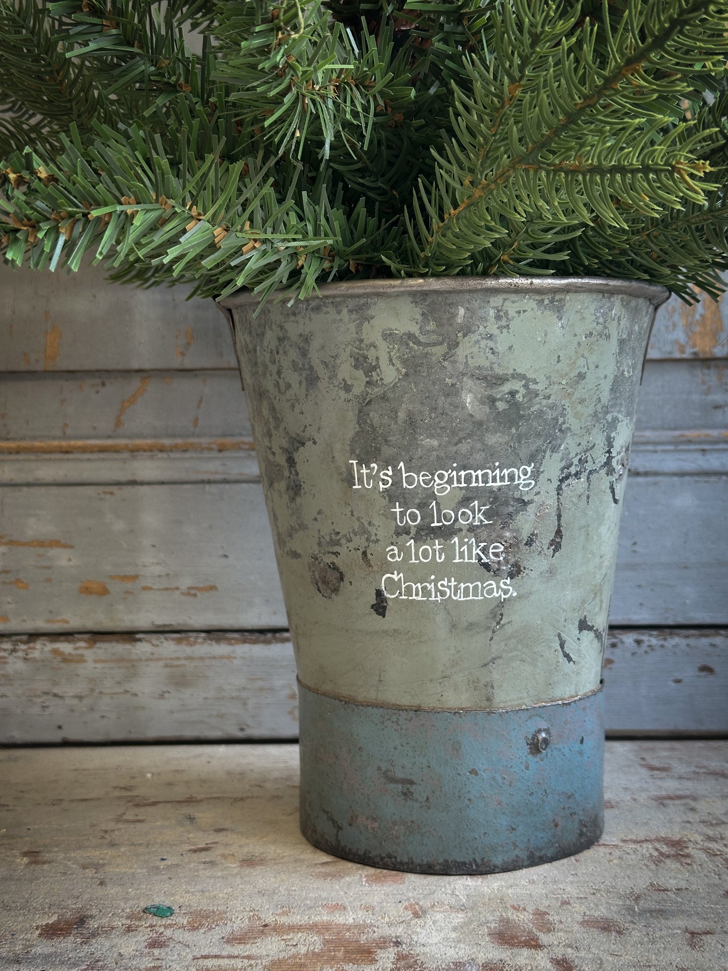 A Recycled Metal Mini Christmas Tree Bucket With A Hand Painted Quote