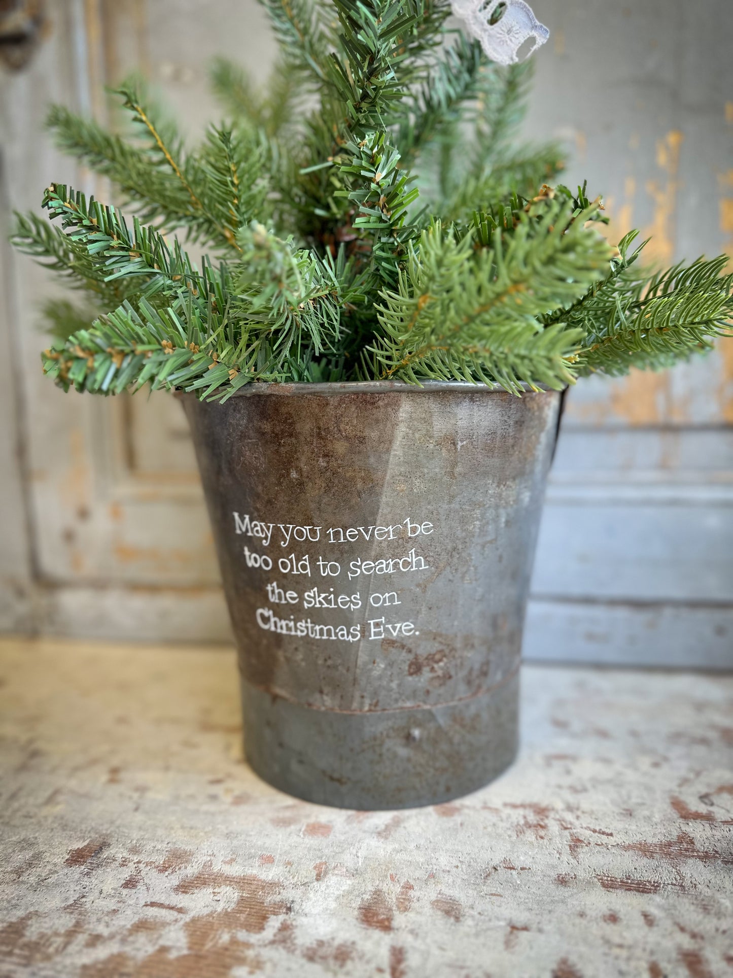 A Recycled Metal Small Christmas Tree Bucket With A Hand Painted Quote