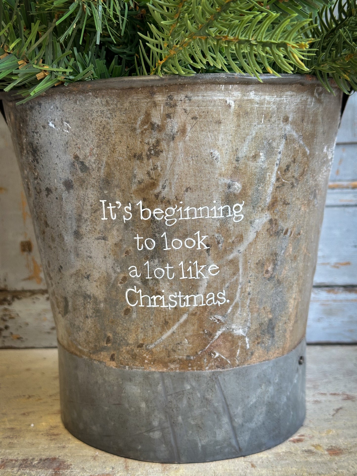 A Recycled Metal Small Christmas Tree Bucket With A Hand Painted Quote