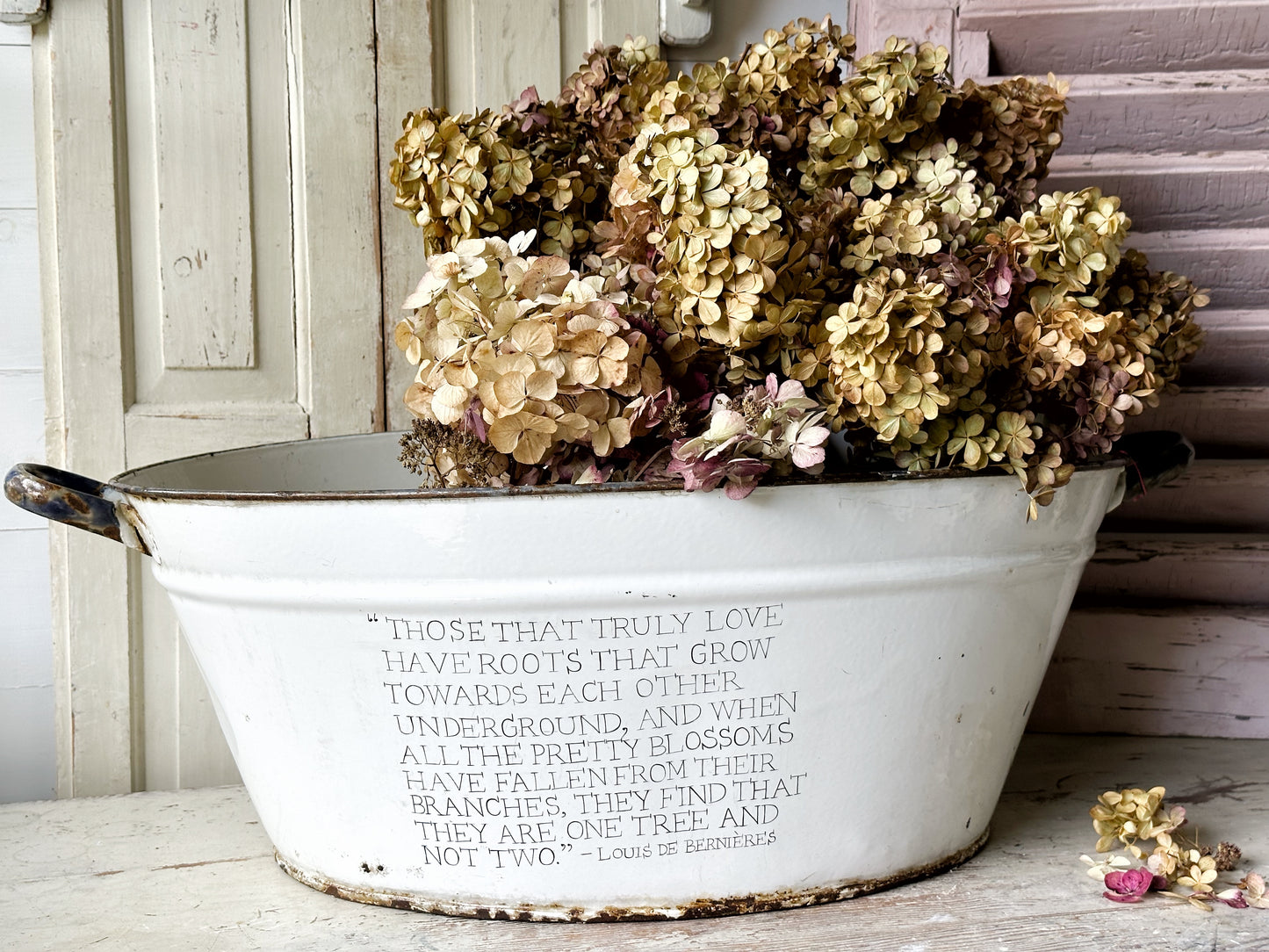 A rustic time worn white enamel oval bath hand painted with a quote.