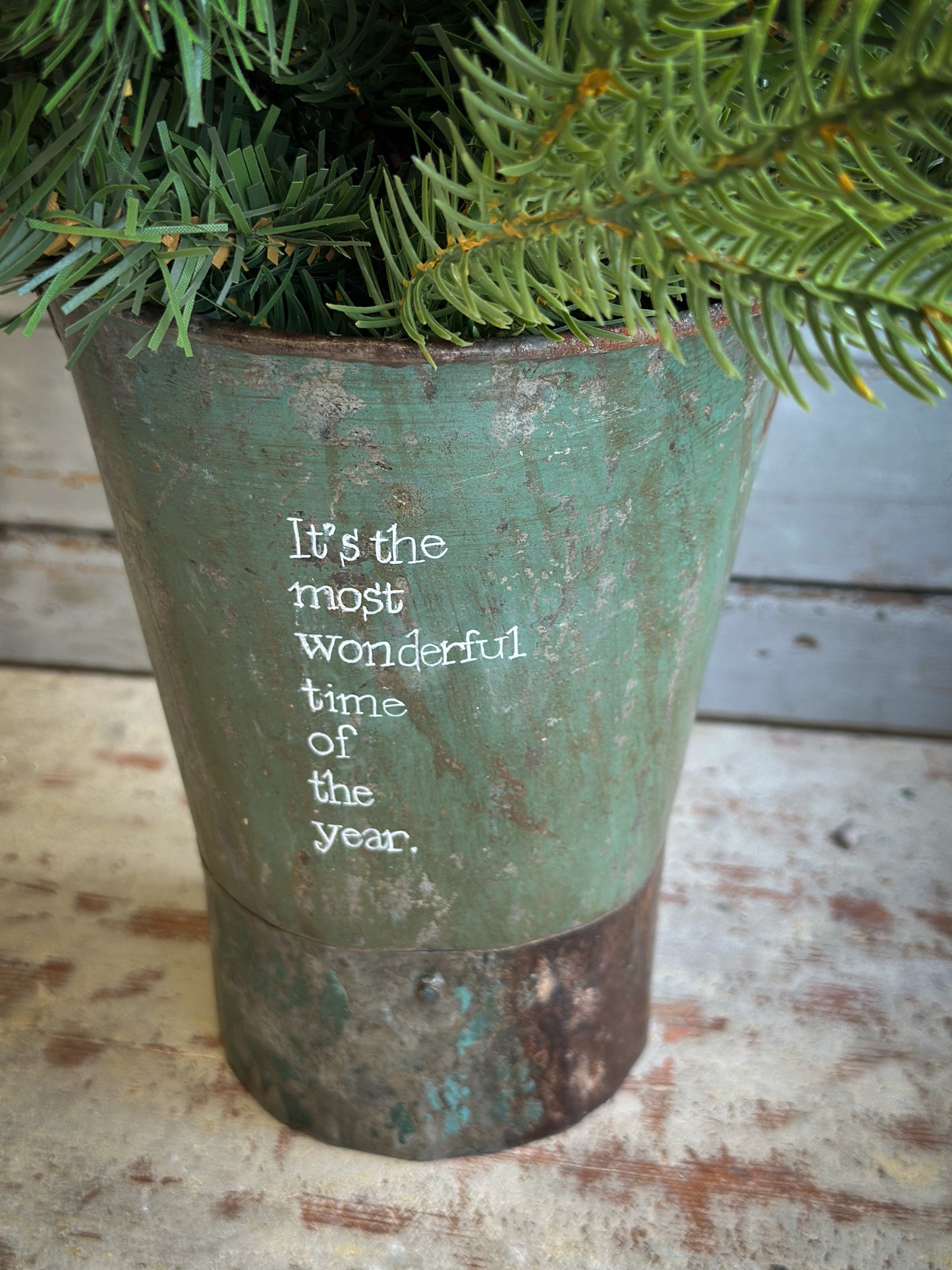 A Recycled Metal Mini Christmas Tree Bucket With A Hand Painted Quote