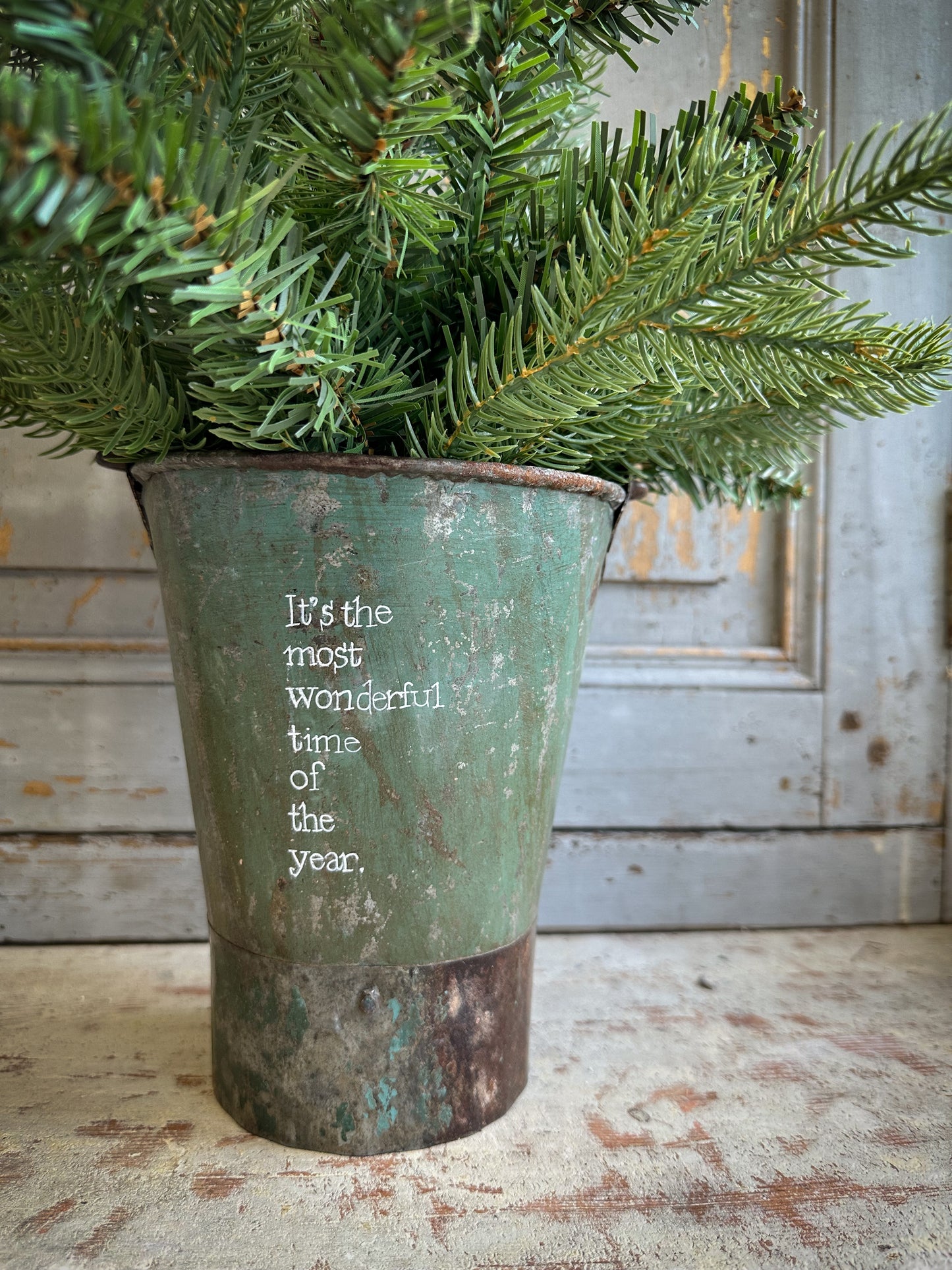A Recycled Metal Mini Christmas Tree Bucket With A Hand Painted Quote