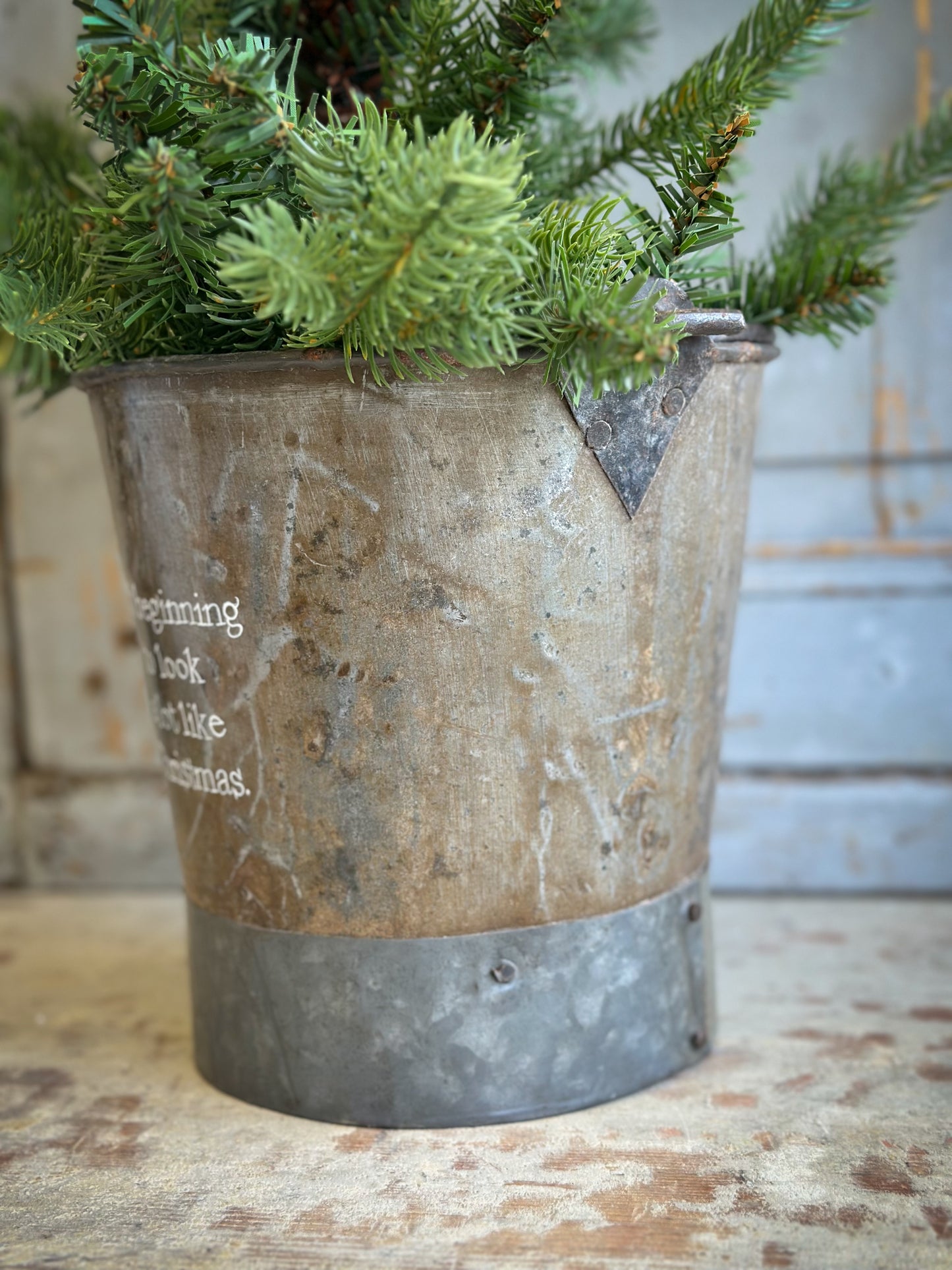 A Recycled Metal Small Christmas Tree Bucket With A Hand Painted Quote
