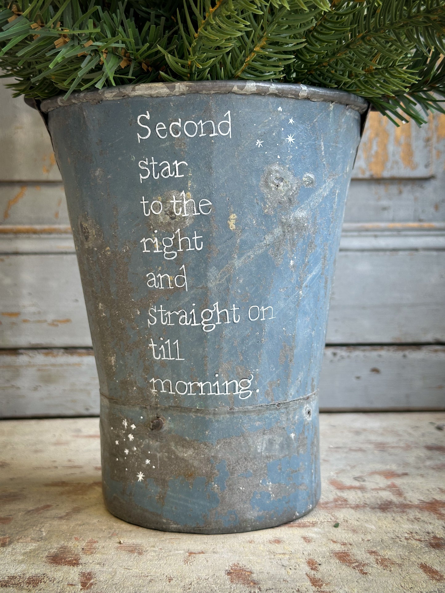 A Recycled Metal Mini Christmas Tree Bucket With A Hand Painted Quote