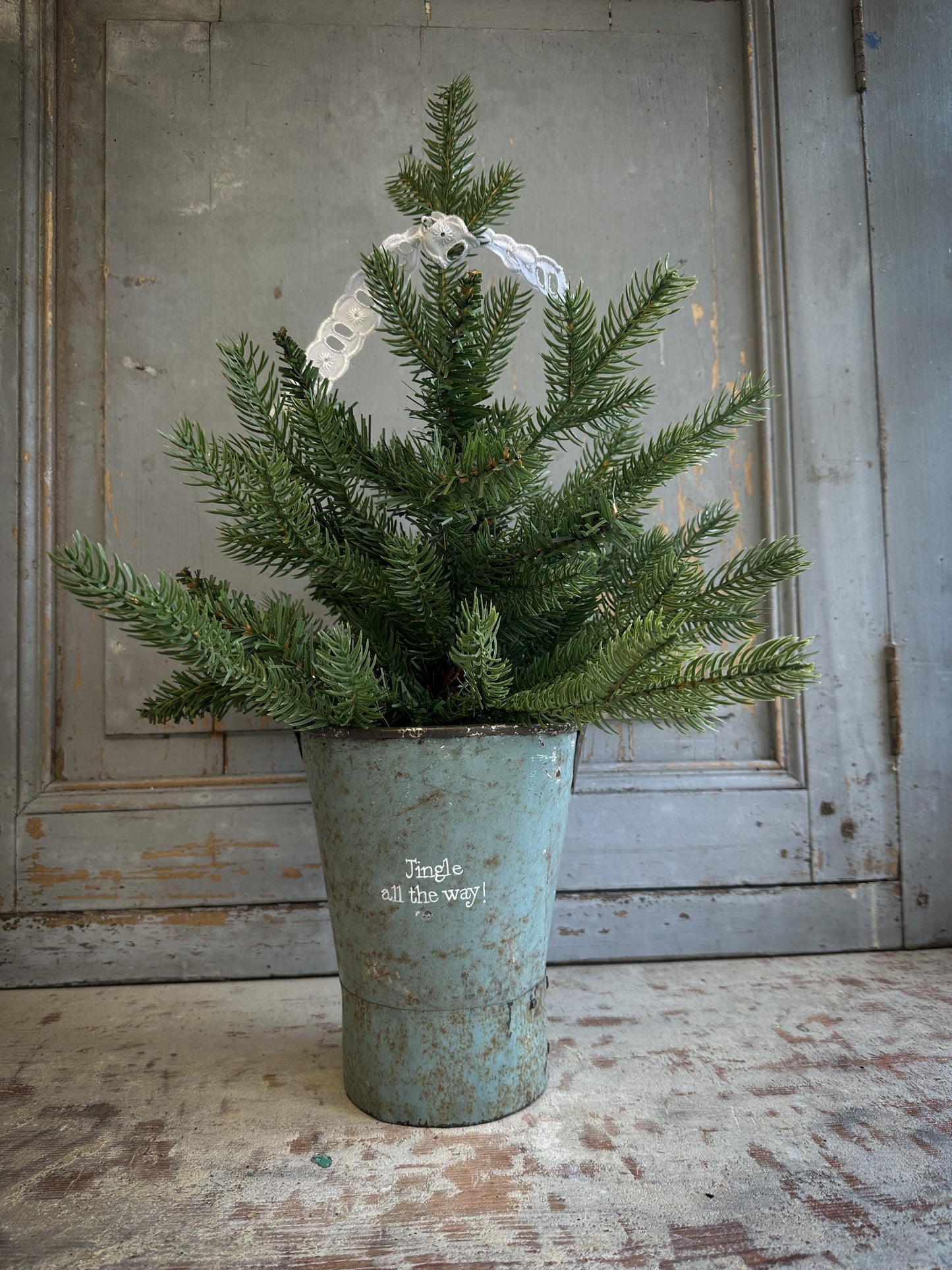 A Recycled Metal Mini Christmas Tree Bucket With A Hand Painted Quote