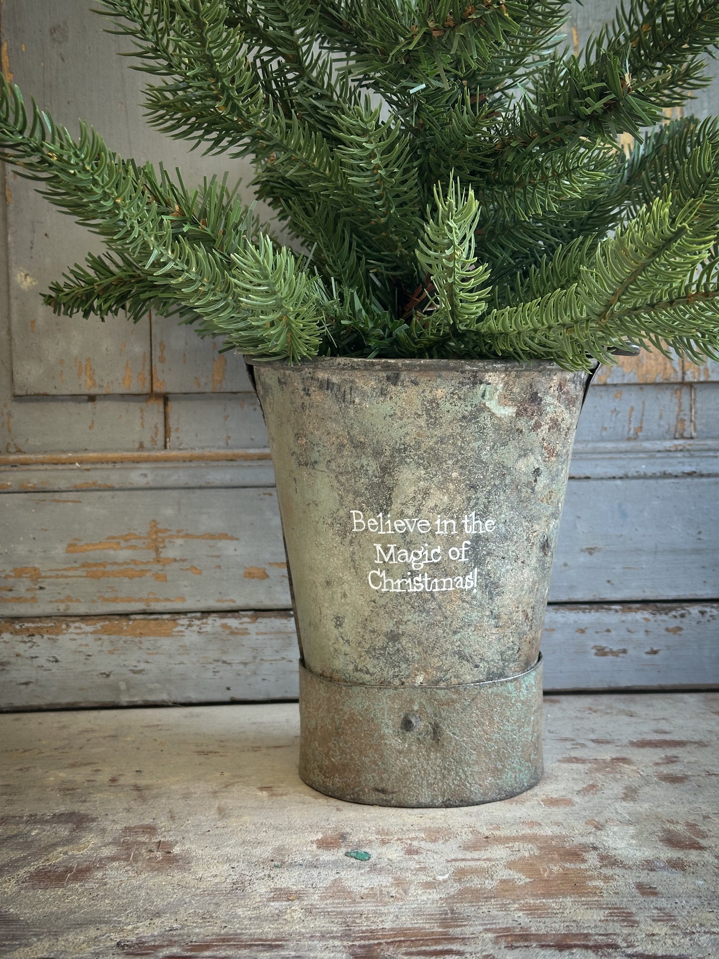 A Recycled Metal Mini Christmas Tree Bucket With A Hand Painted Quote