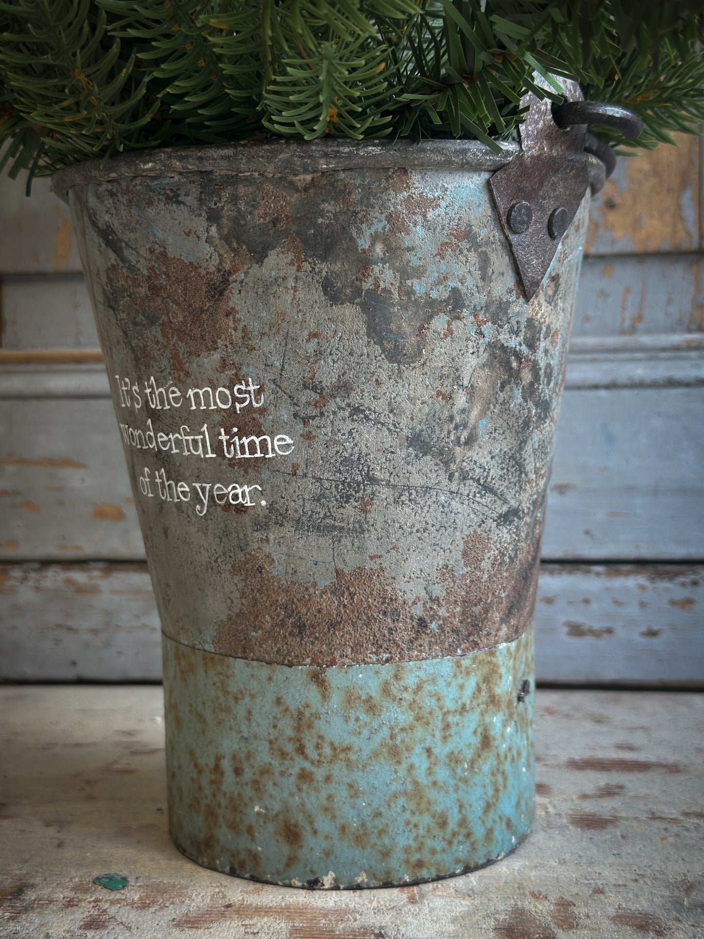 A Recycled Metal Mini Christmas Tree Bucket With A Hand Painted Quote