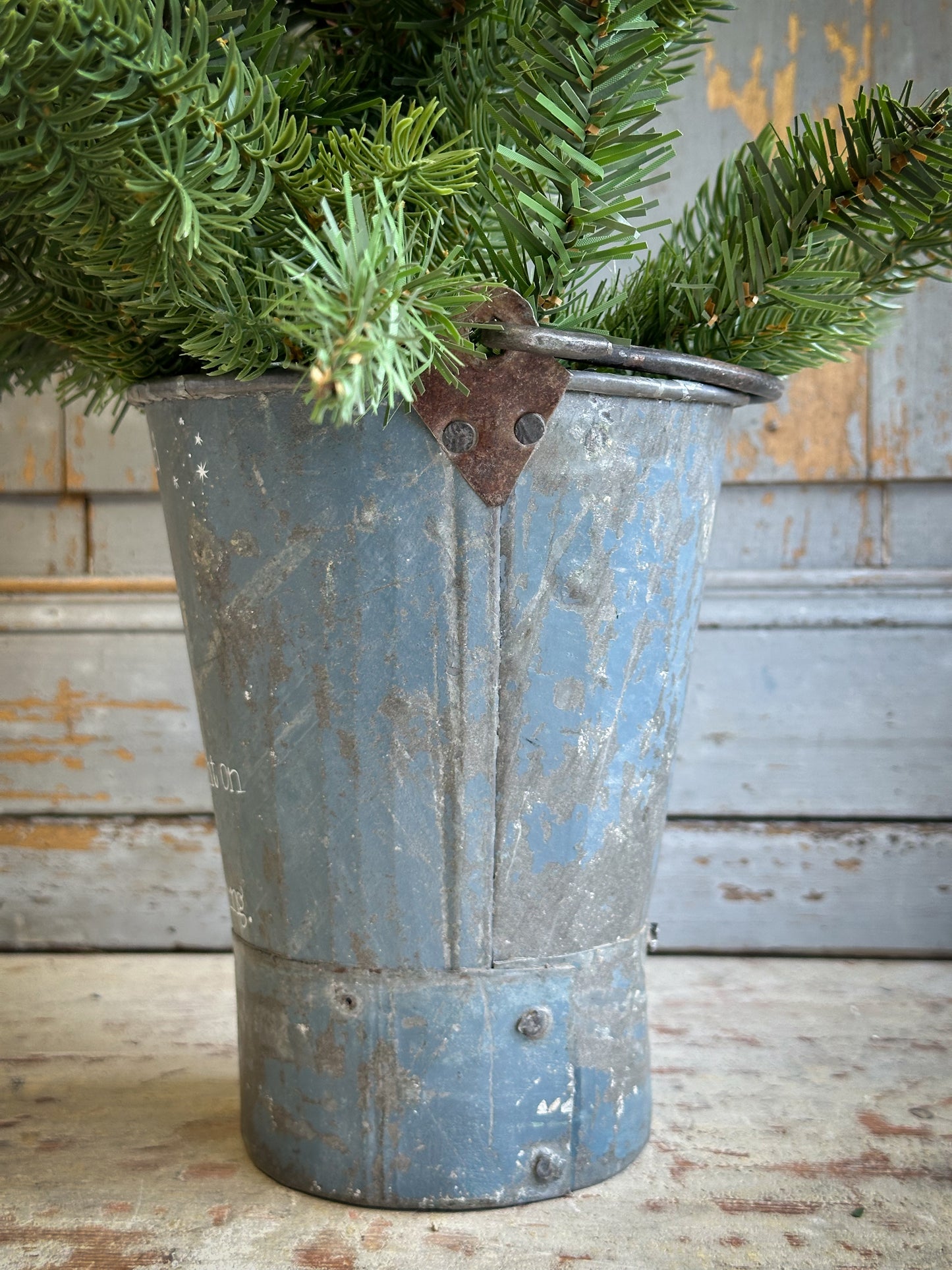 A Recycled Metal Mini Christmas Tree Bucket With A Hand Painted Quote
