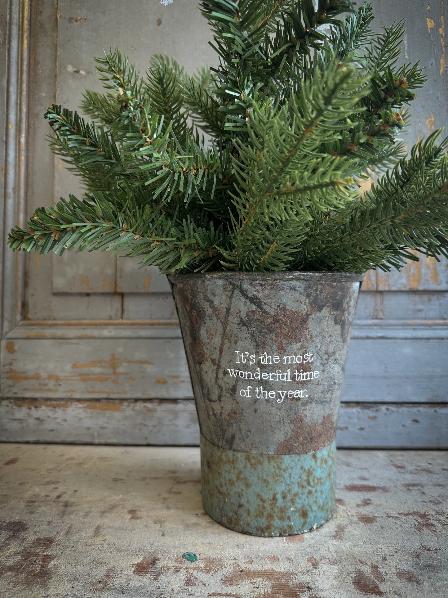 A Recycled Metal Mini Christmas Tree Bucket With A Hand Painted Quote