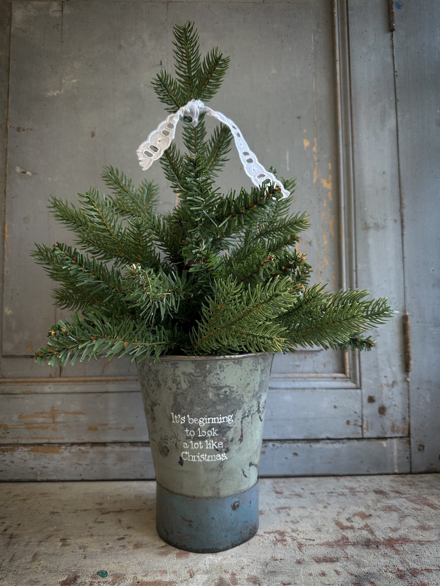 A Recycled Metal Mini Christmas Tree Bucket With A Hand Painted Quote