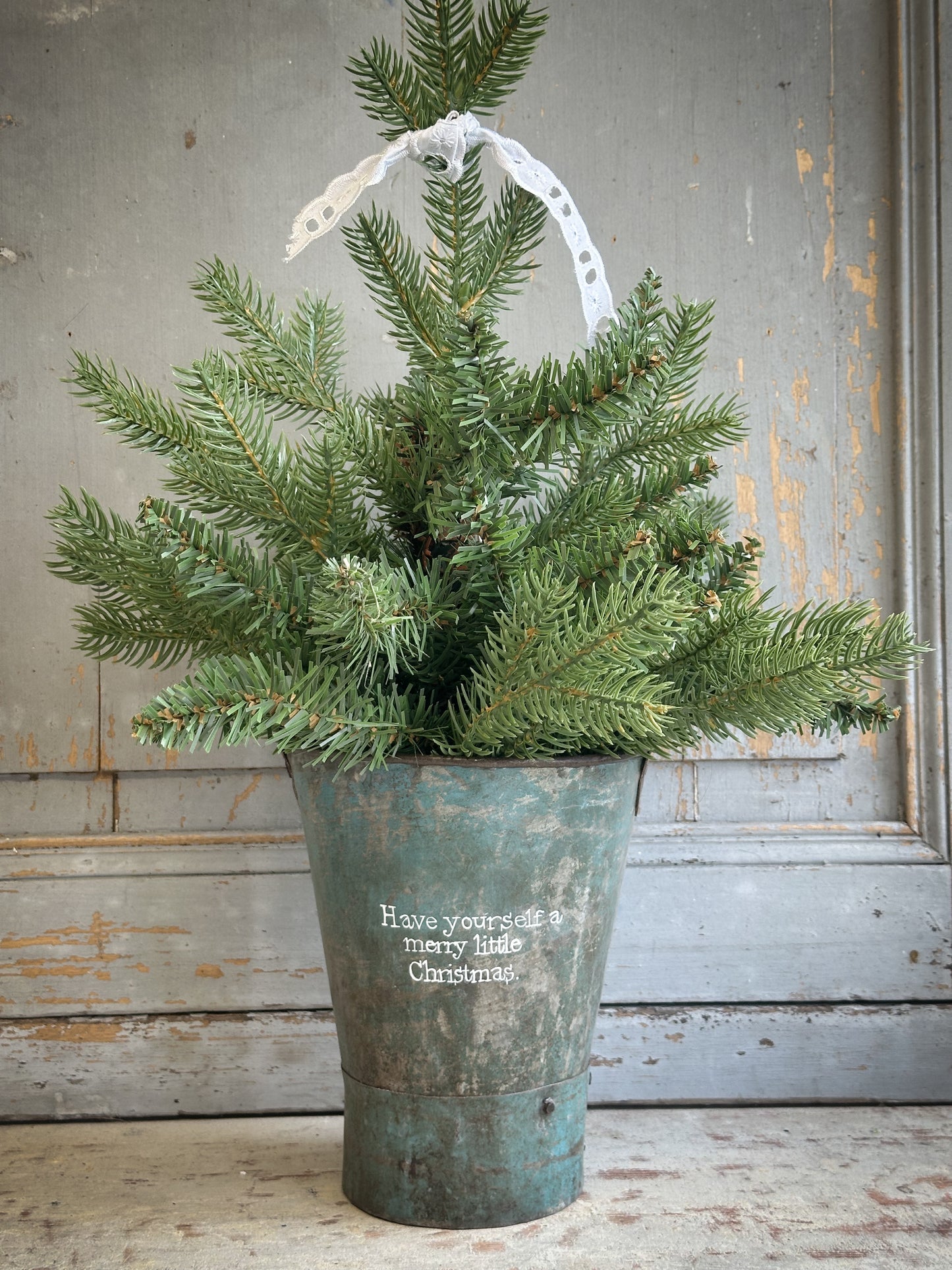 A Recycled Metal Mini Christmas Tree Bucket With A Hand Painted Quote