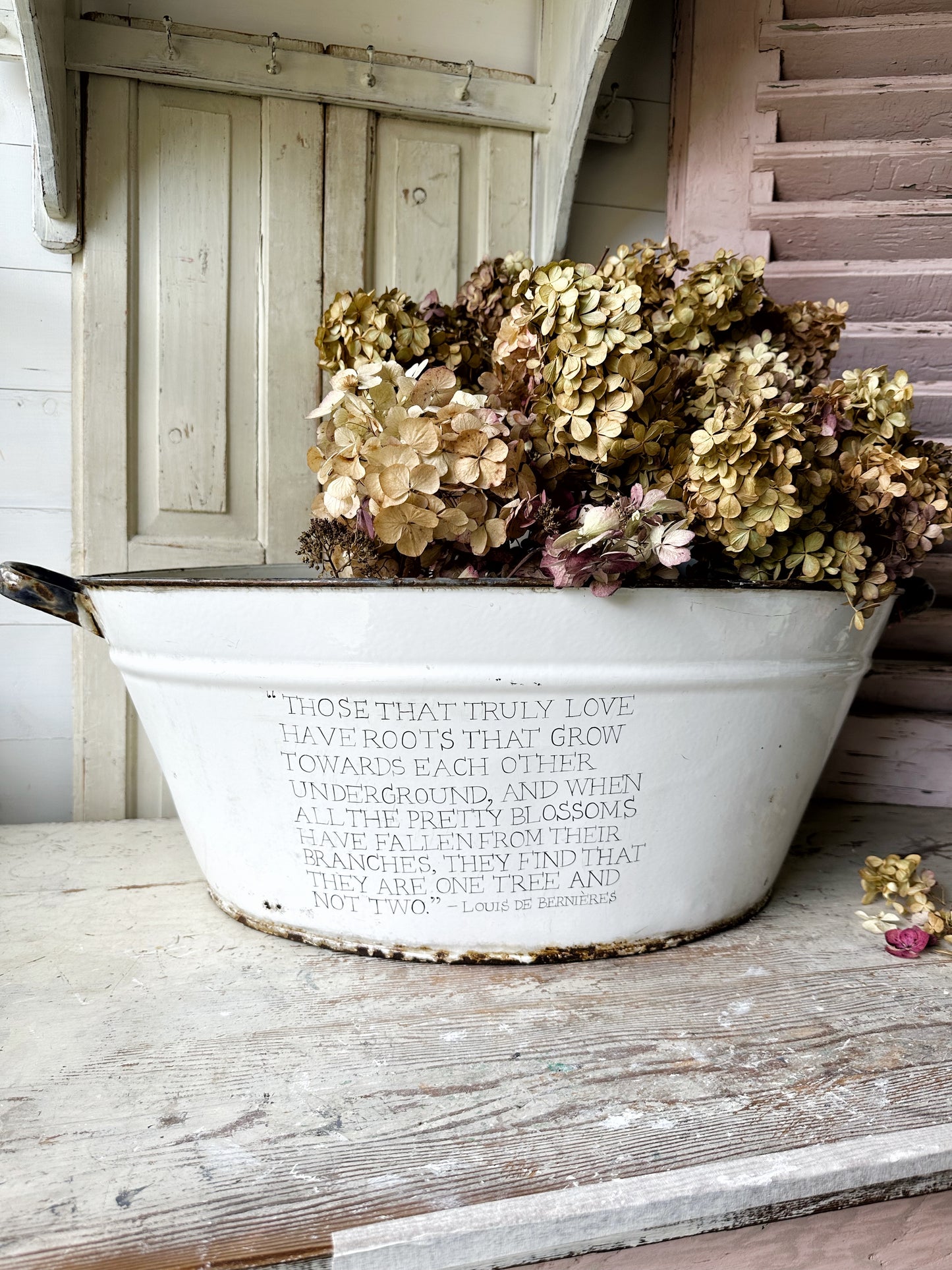 A rustic time worn white enamel oval bath hand painted with a quote.