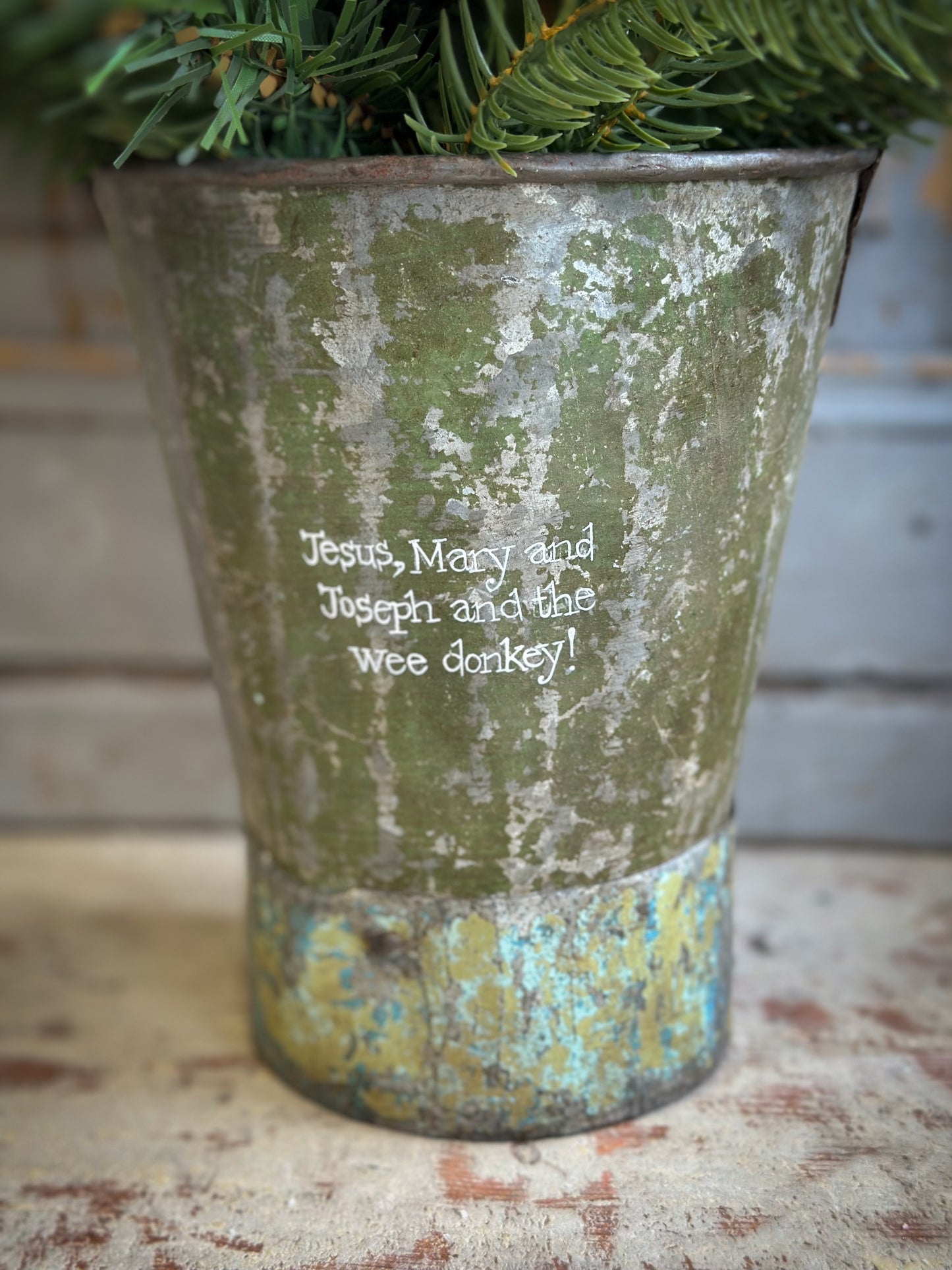 A Recycled Metal Mini Christmas Tree Bucket With A Hand Painted Quote