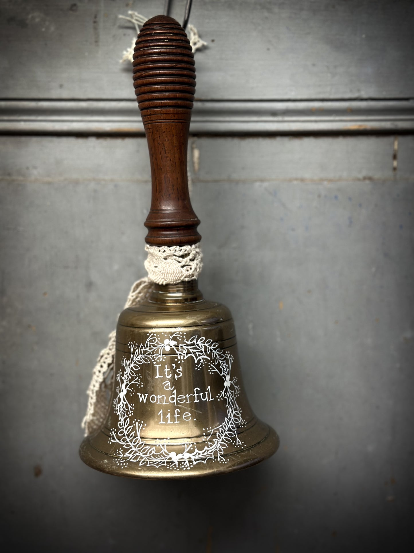 A vintage brass hand held bell with a hand painted quote