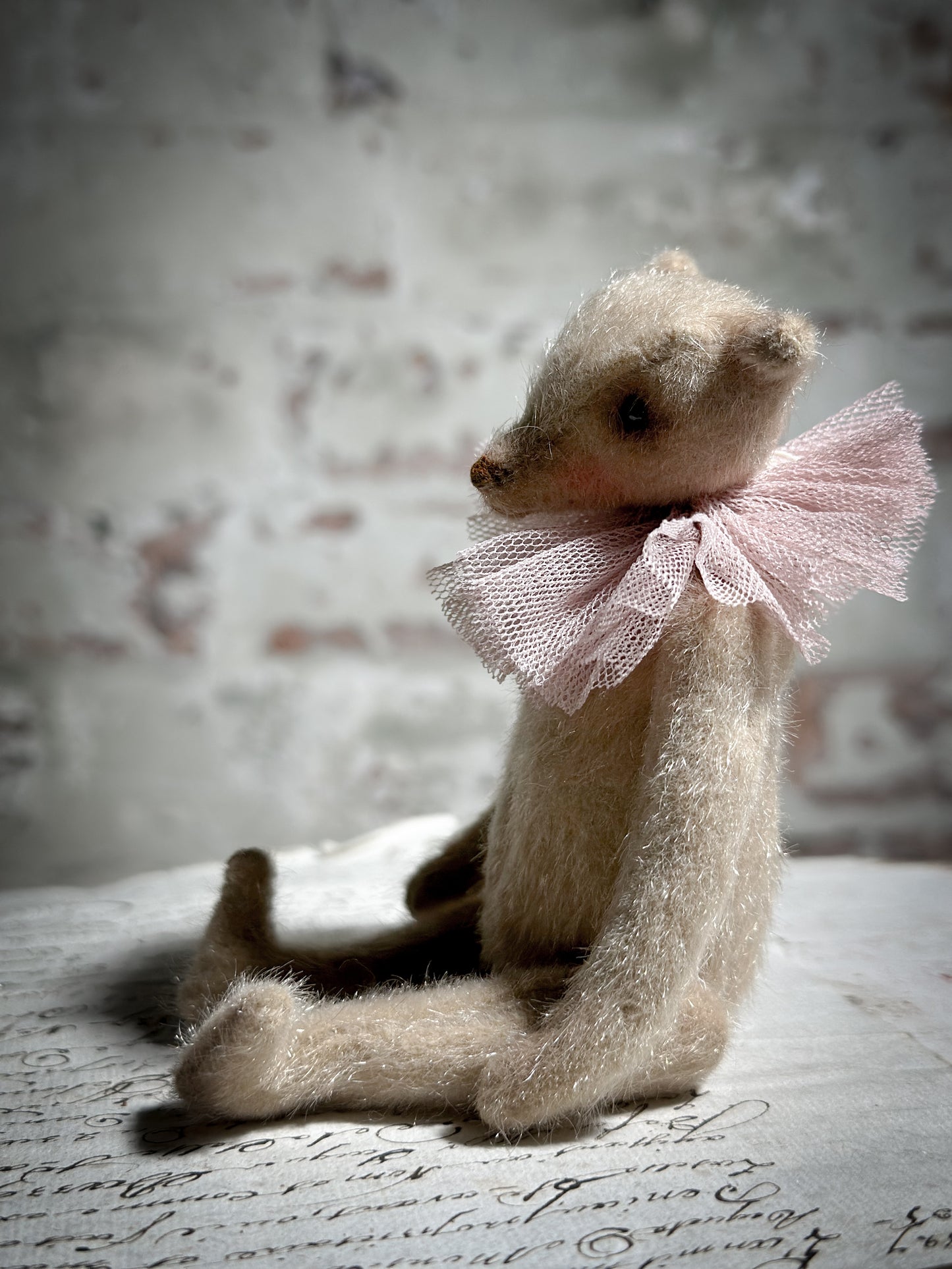 A beautiful hand made jointed collector’s teddy bear with antique pink tulle ruffle