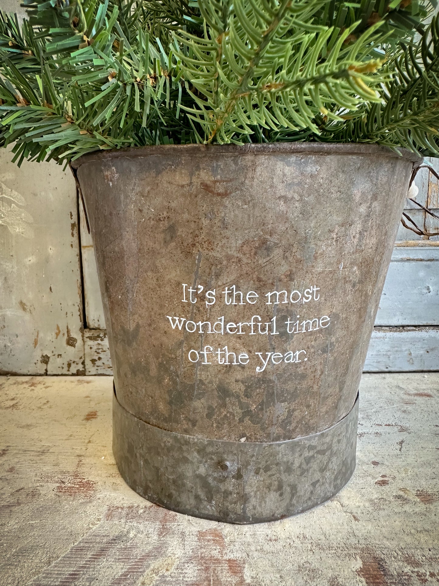 A Recycled Metal Small Christmas Tree Bucket With A Hand Painted Quote