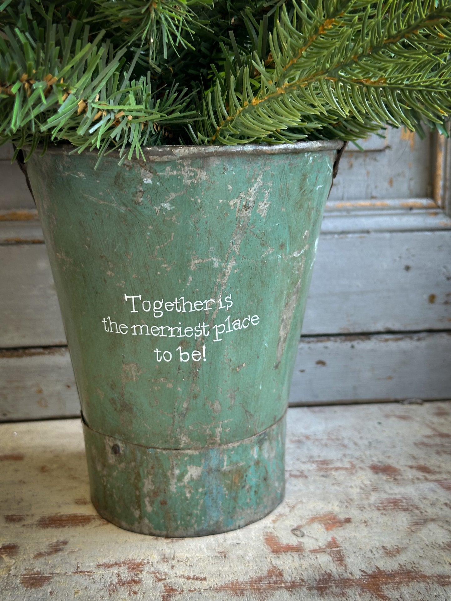 A Recycled Metal Mini Christmas Tree Bucket With A Hand Painted Quote