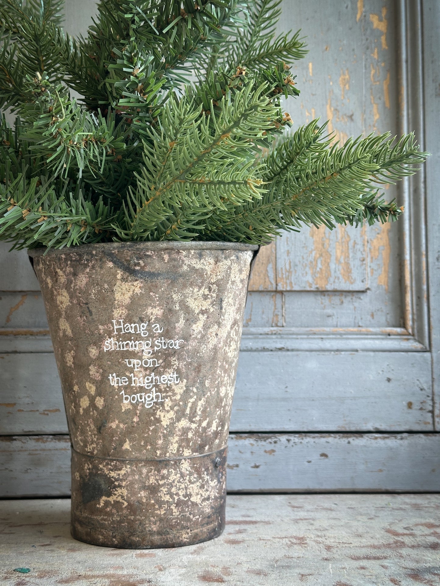 A Recycled Metal Mini Christmas Tree Bucket With A Hand Painted Quote
