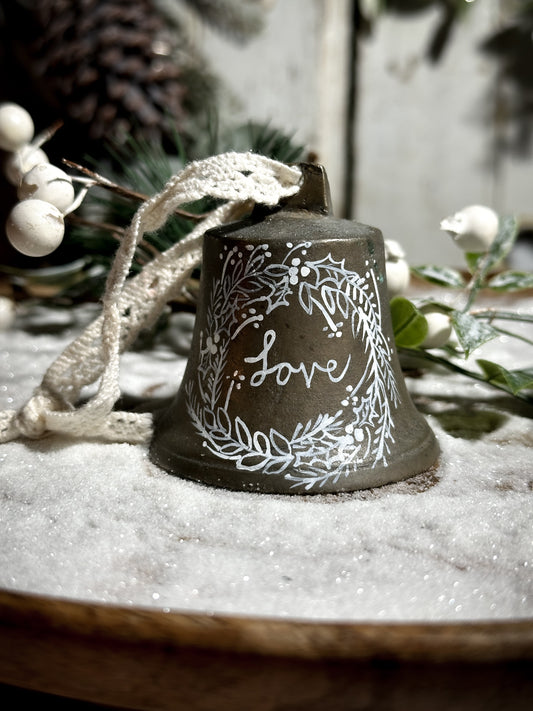 A vintage brass bell with a hand painted quote