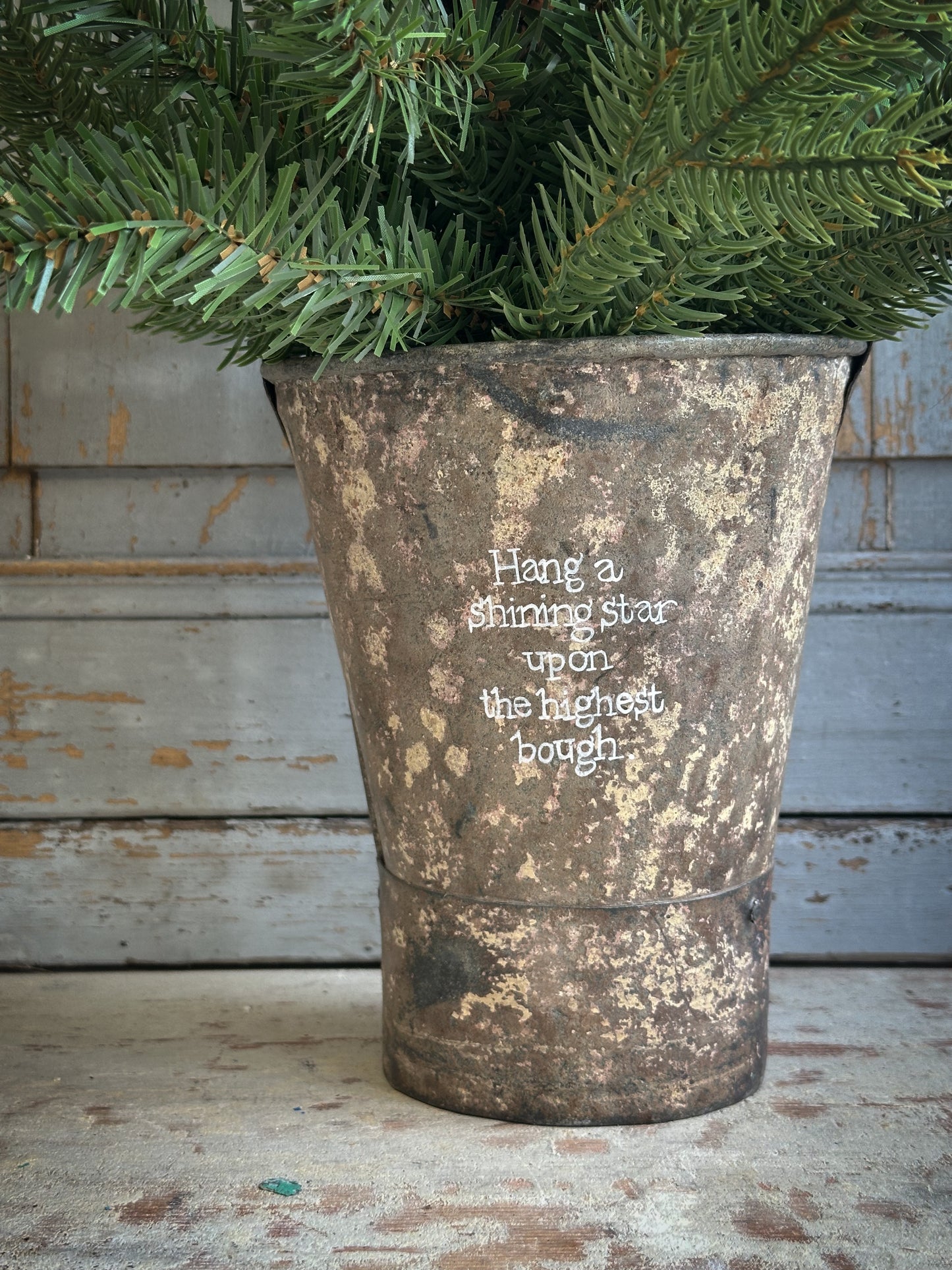 A Recycled Metal Mini Christmas Tree Bucket With A Hand Painted Quote