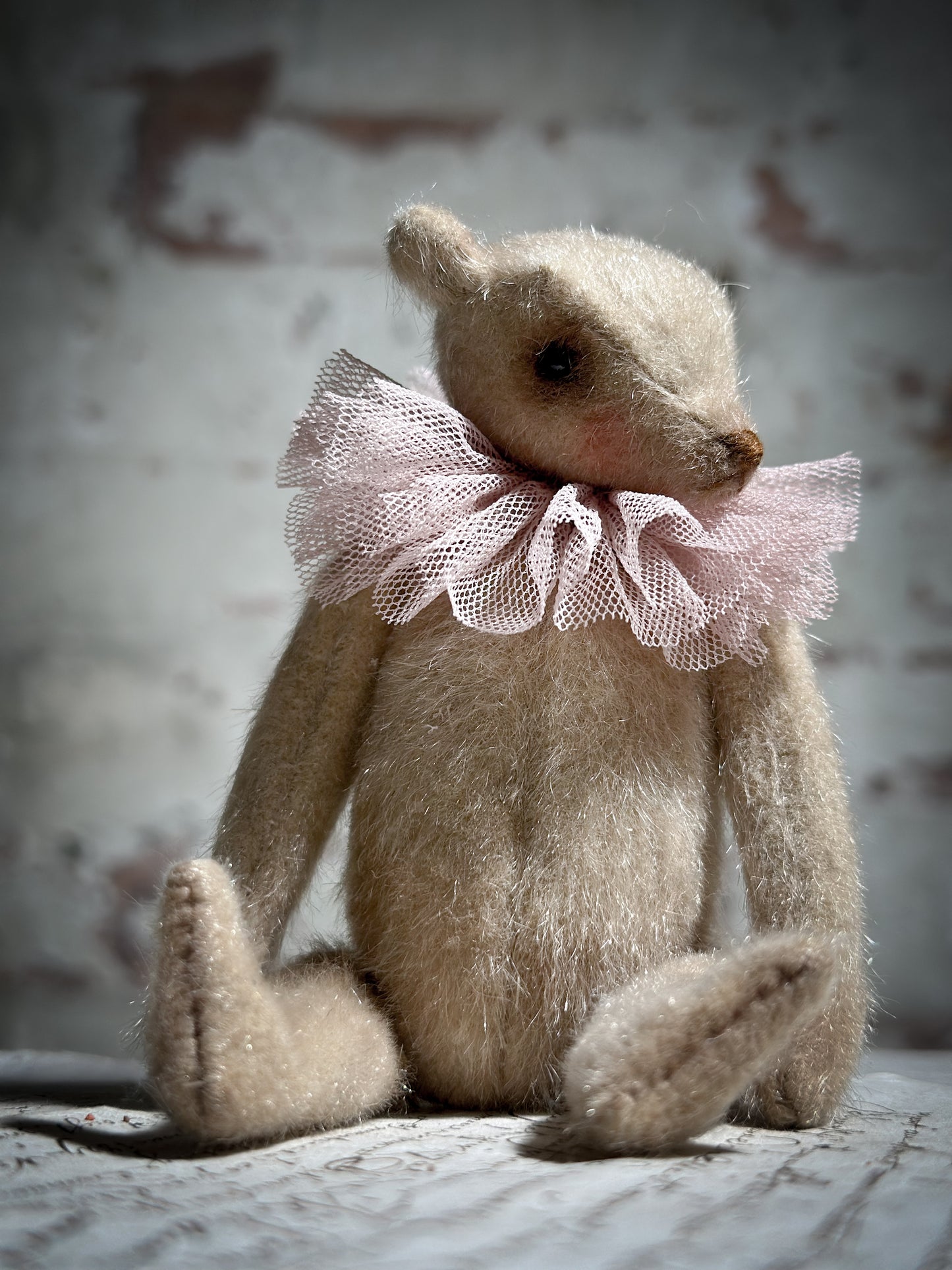 A beautiful hand made jointed collector’s teddy bear with antique pink tulle ruffle